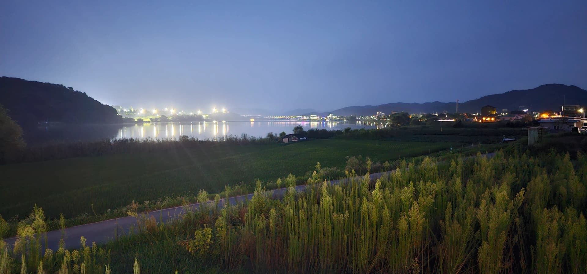 카페 반내에서 바라본 남한강 야경 — 강 건너 충주 시내 불빛이 수면 위로 번지는 모습