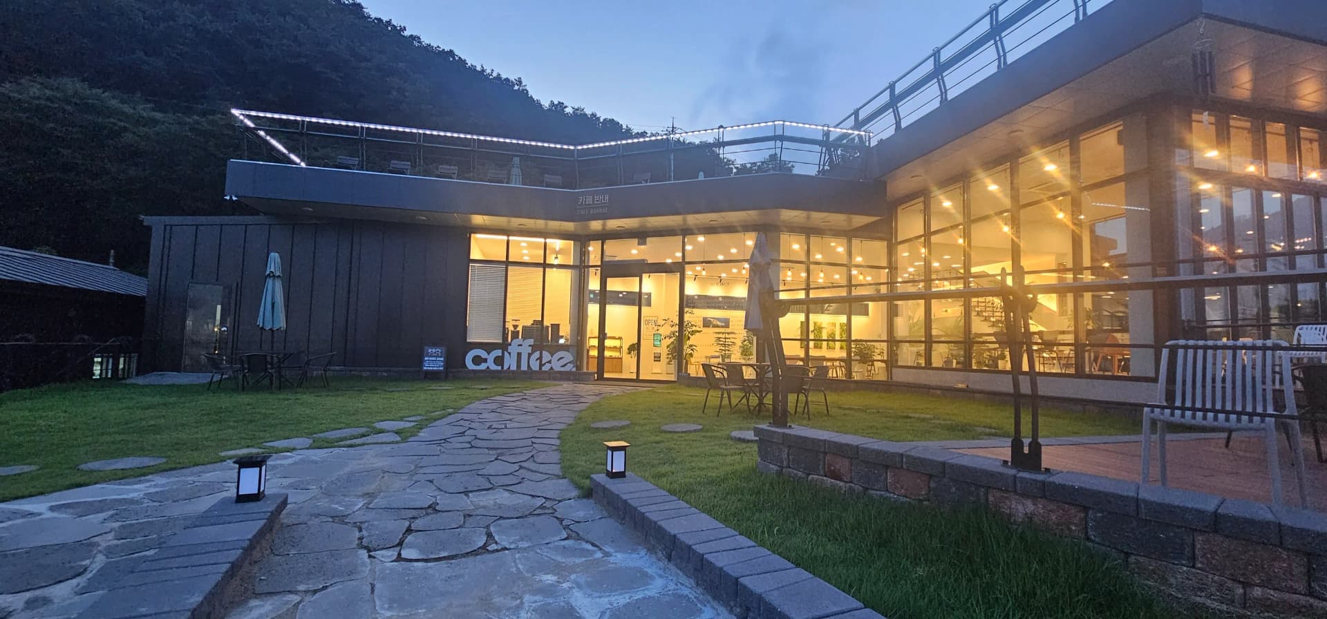 카페 반내 야외 잔디밭과 돌길 — 바닥 조명이 켜진 저녁 풍경