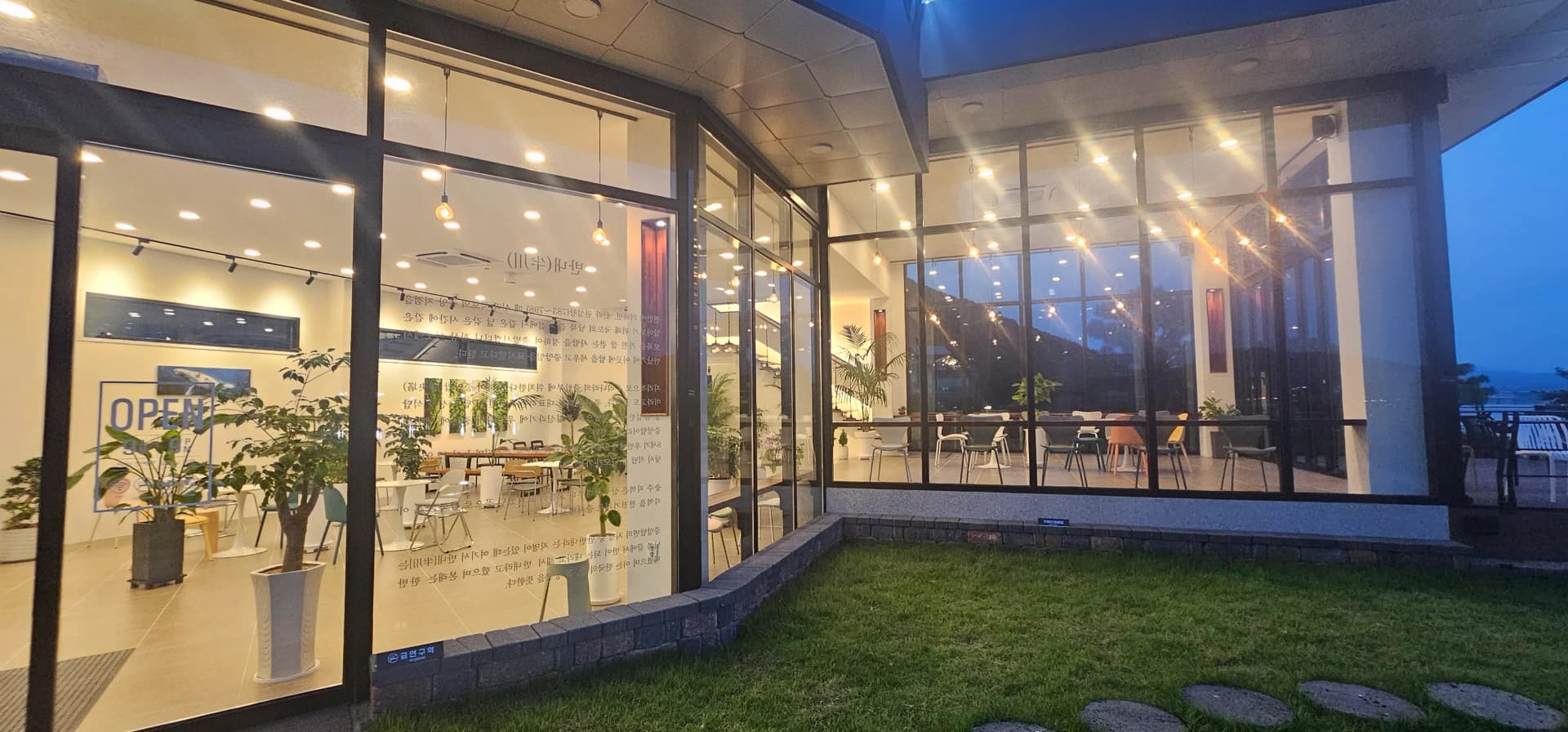 카페 반내 외부 측면 — 유리창에 적힌 카페 이름과 조명이 비치는 저녁 모습