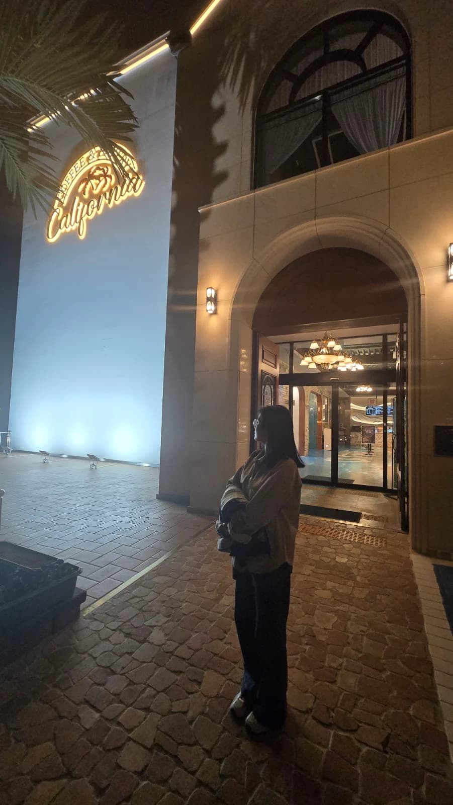 카페 캘리포니아 입구 네온 간판과 샹들리에가 보이는 아치형 문