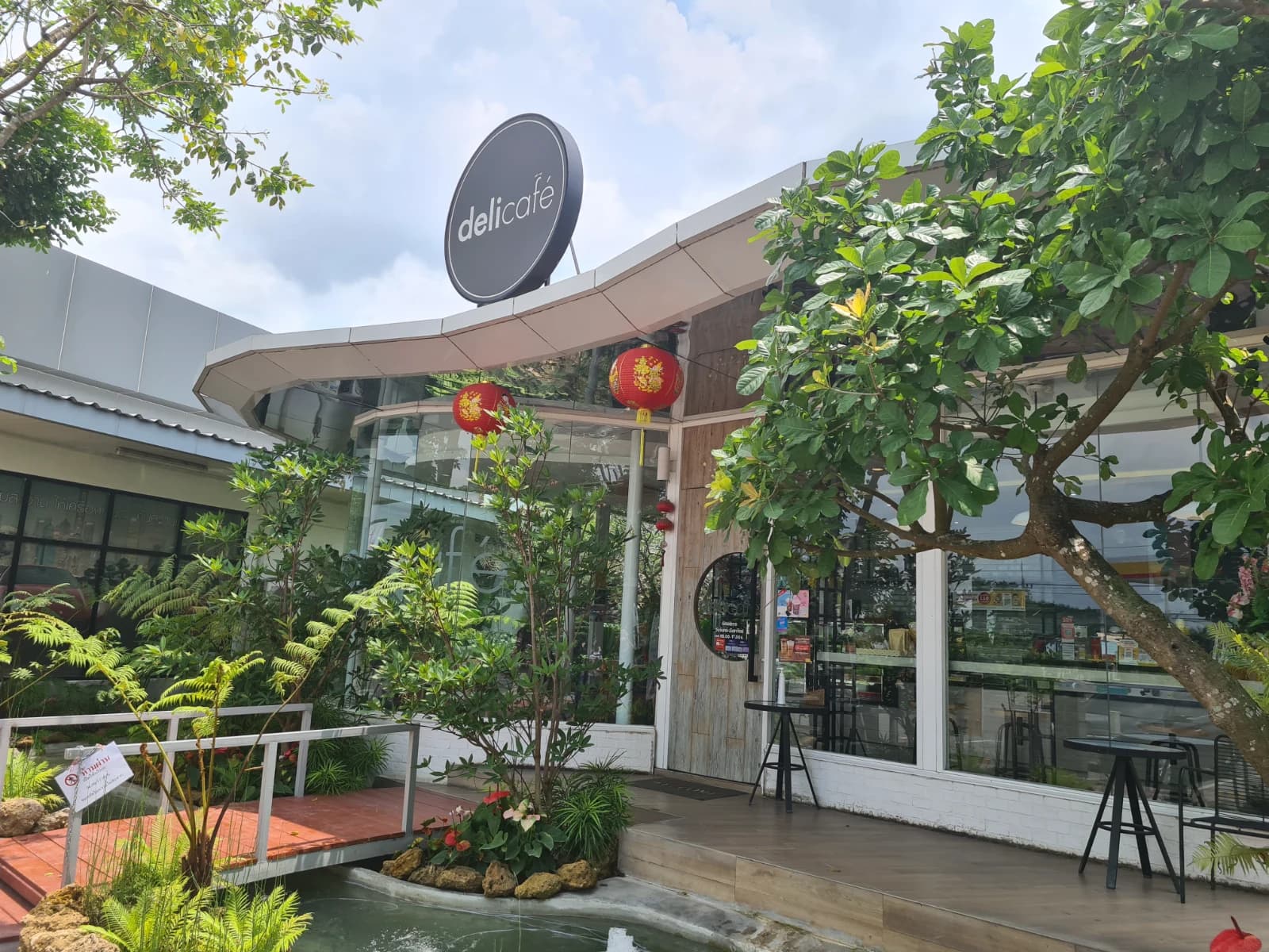 delicafé 외관, 입구 앞 연못과 초록 식물이 꾸며진 태국 Shell 주유소 카페