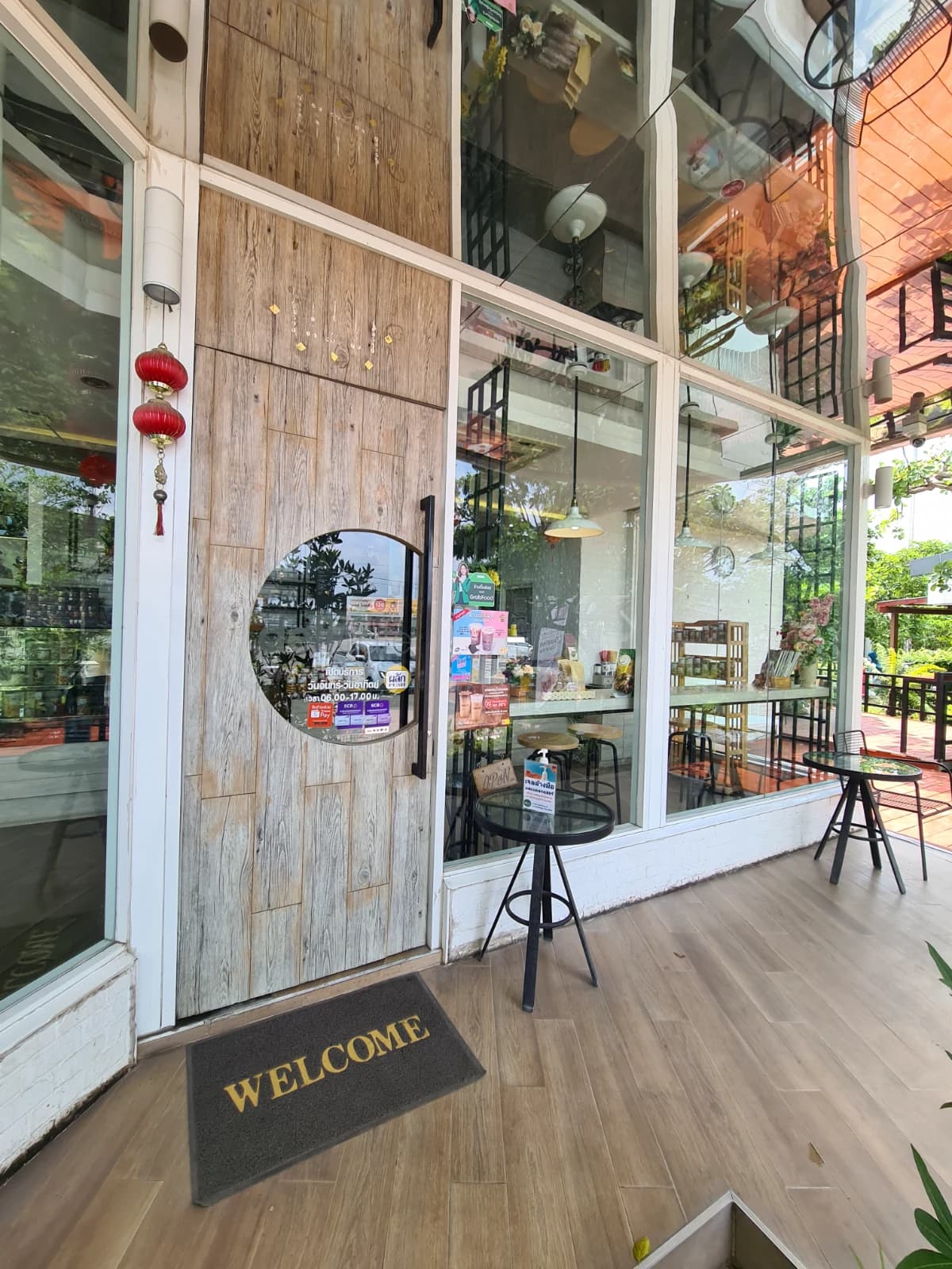 delicafé 입구 나무문과 원형 창문, WELCOME 매트가 깔린 카페 출입구