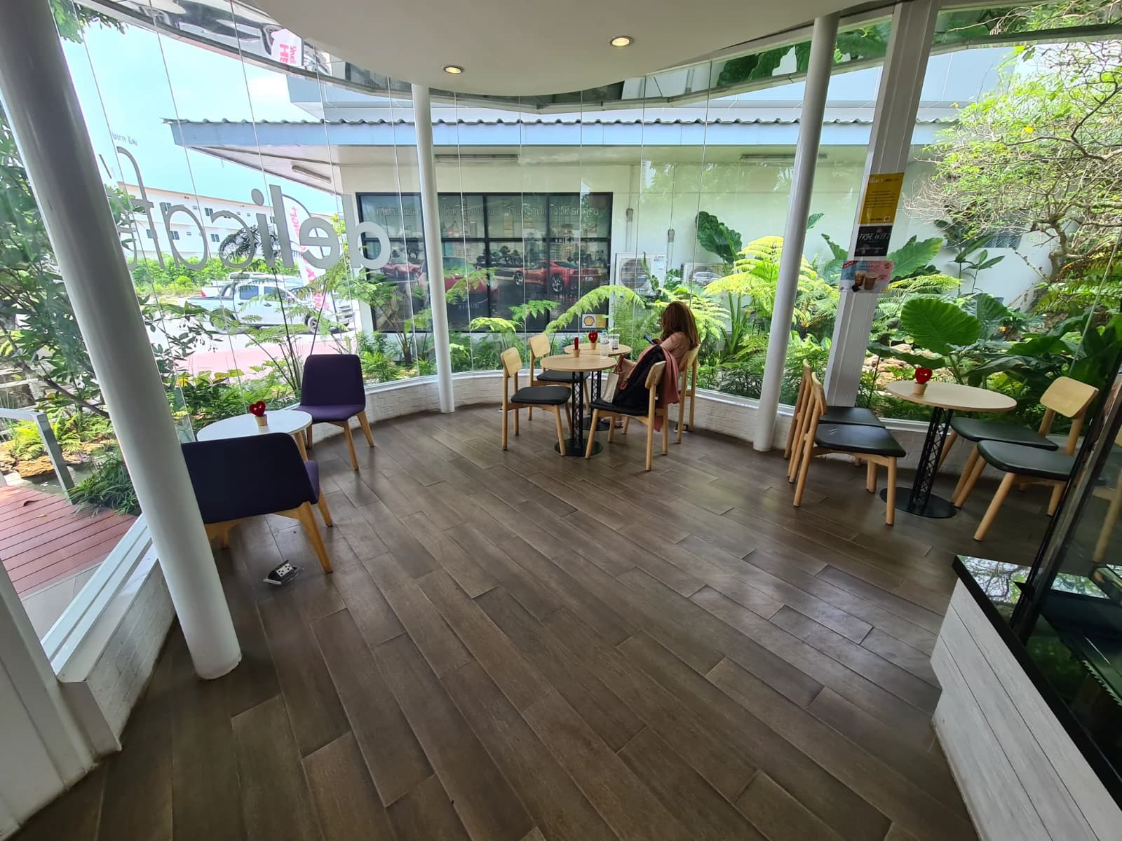 delicafé 내부 통유리 창가 좌석, 바깥 초록 식물이 보이는 태국 주유소 카페