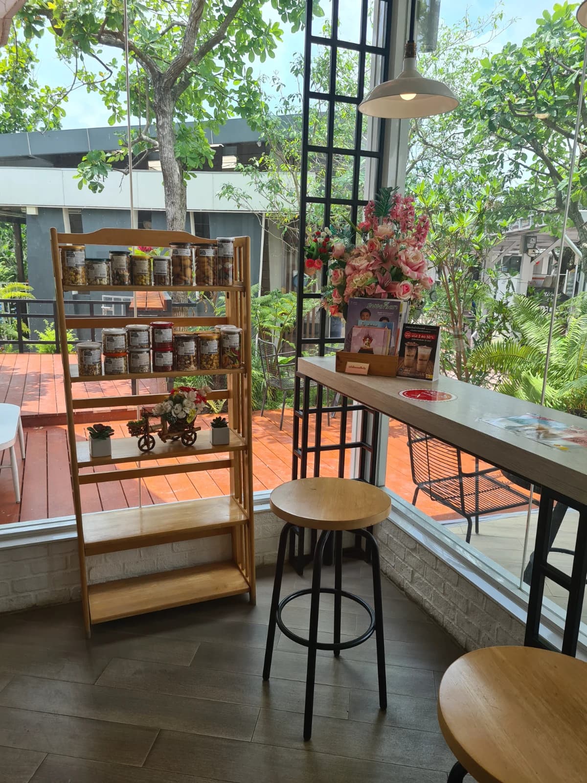 delicafé 창가 나무 선반과 간식 진열, 유리 너머 초록빛이 들어오는 실내