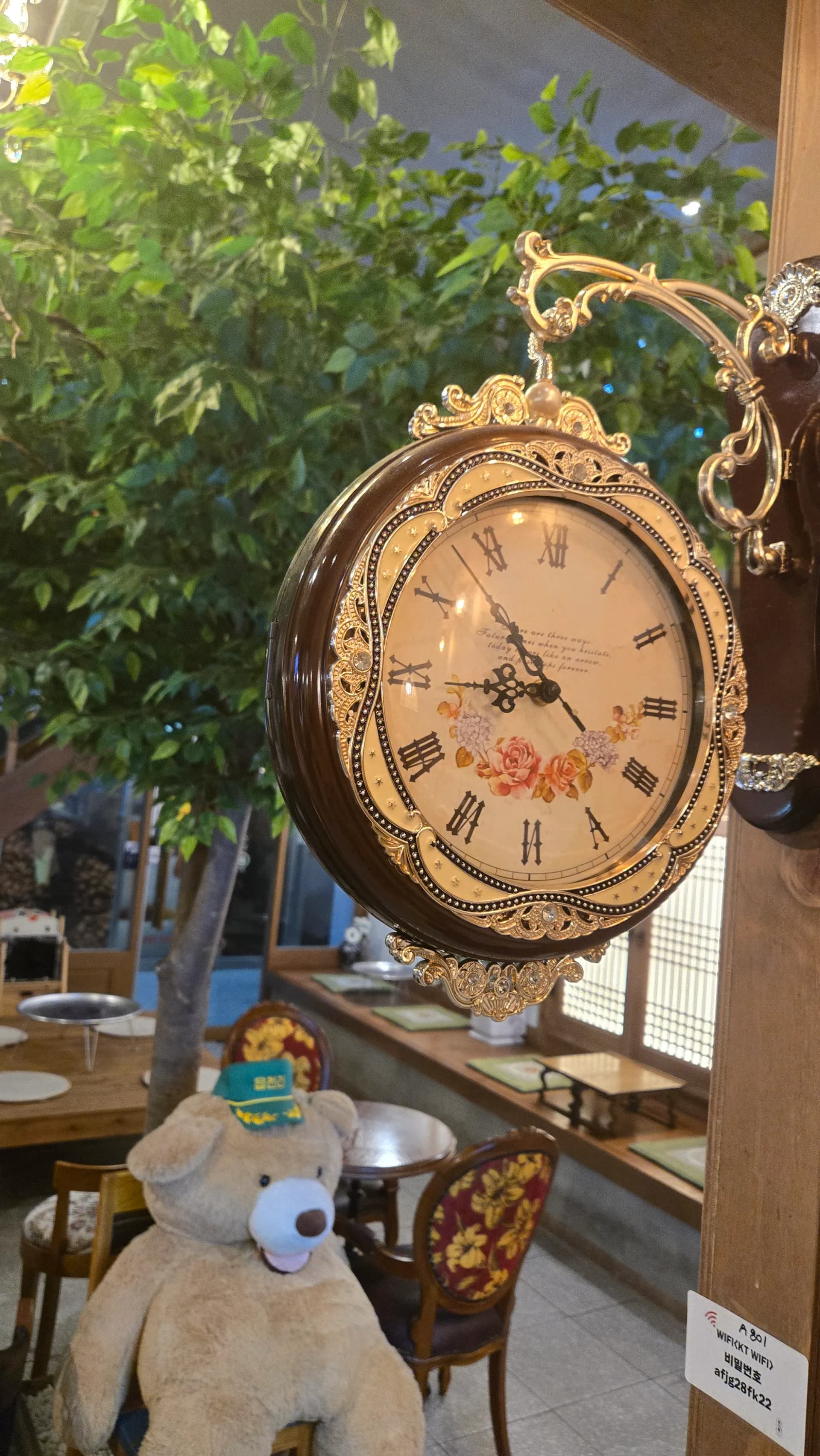 읍천리382 양면 시계와 곰 인형 — 금색 장식 오래된 시계 아래 읍천리 모자를 쓴 대형 곰 인형 | 하이제이에스비