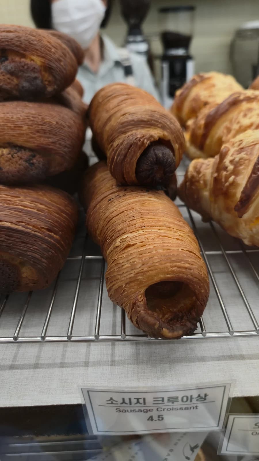 Green Bakery sausage croissant with tightly layered dough about three twenty