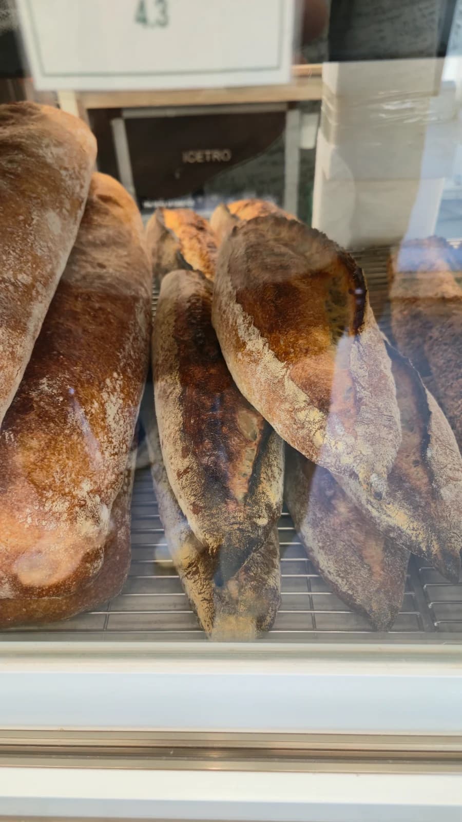 Green Bakery baguette display shelf with artisan hard bread lineup