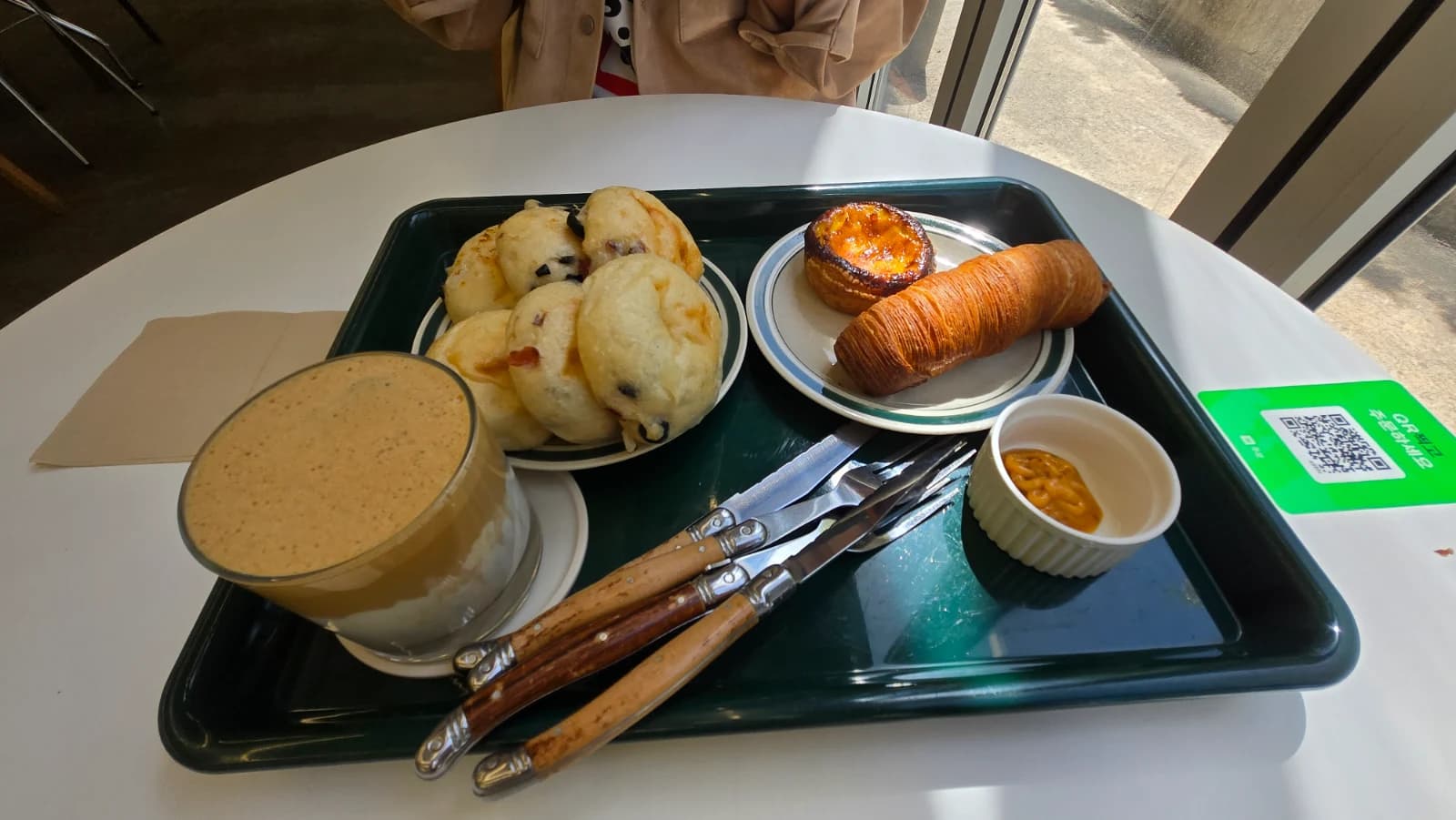 Tray with scone egg tart sausage croissant and coffee at Green Bakery