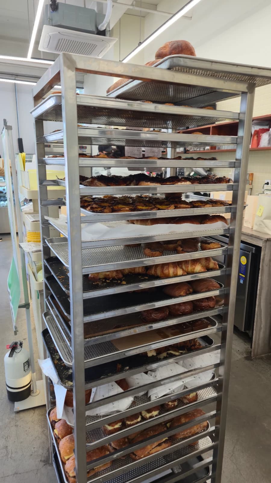 Metal cooling rack next to Green Bakery counter packed with freshly baked bread