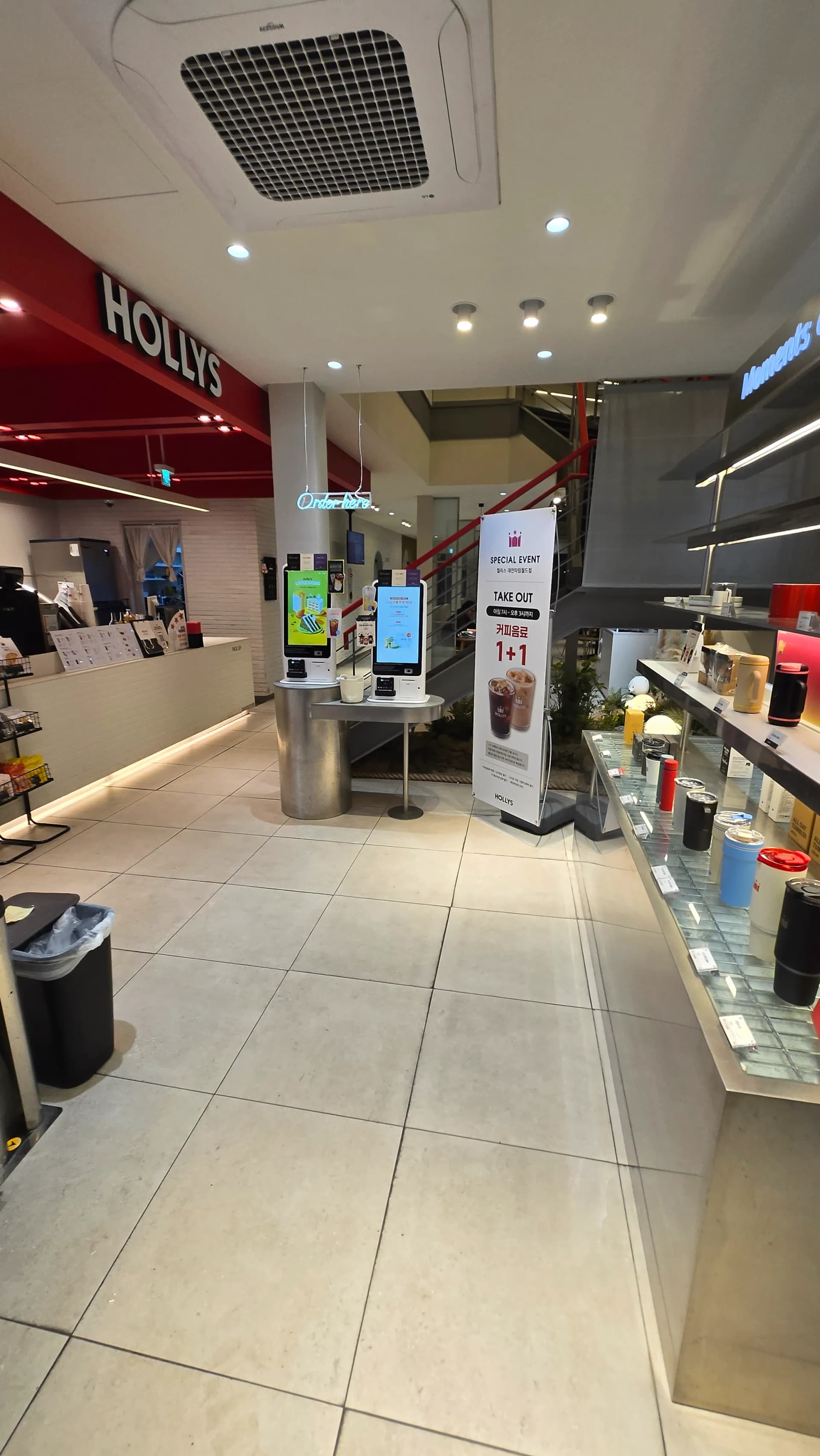 할리스 커피 1층 매장 내부 전경으로 카운터와 키오스크 굿즈 선반이 보인다