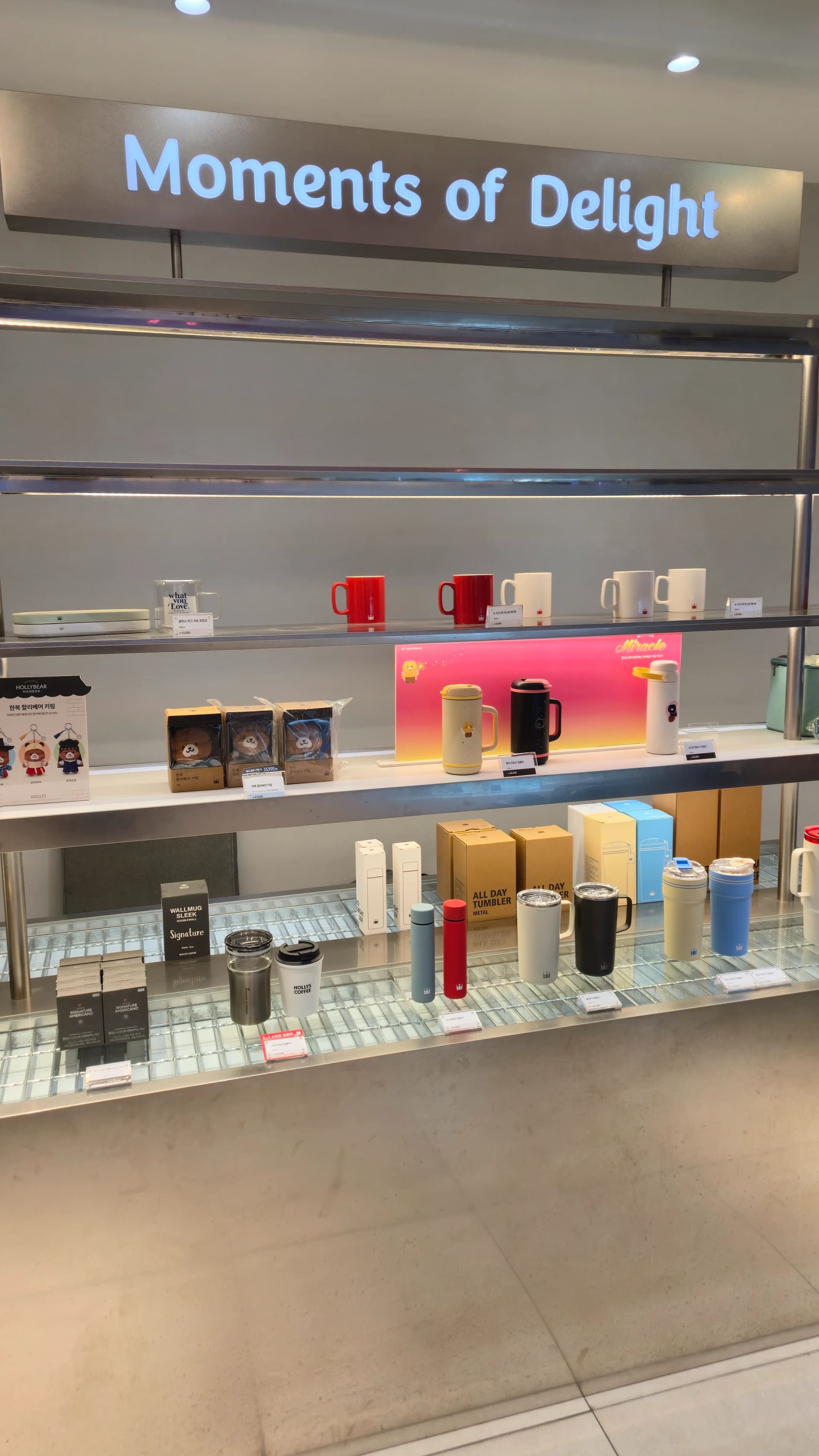 할리스 1층 입구 Moments of Delight 굿즈 진열대에 텀블러와 머그컵이 진열되어 있다