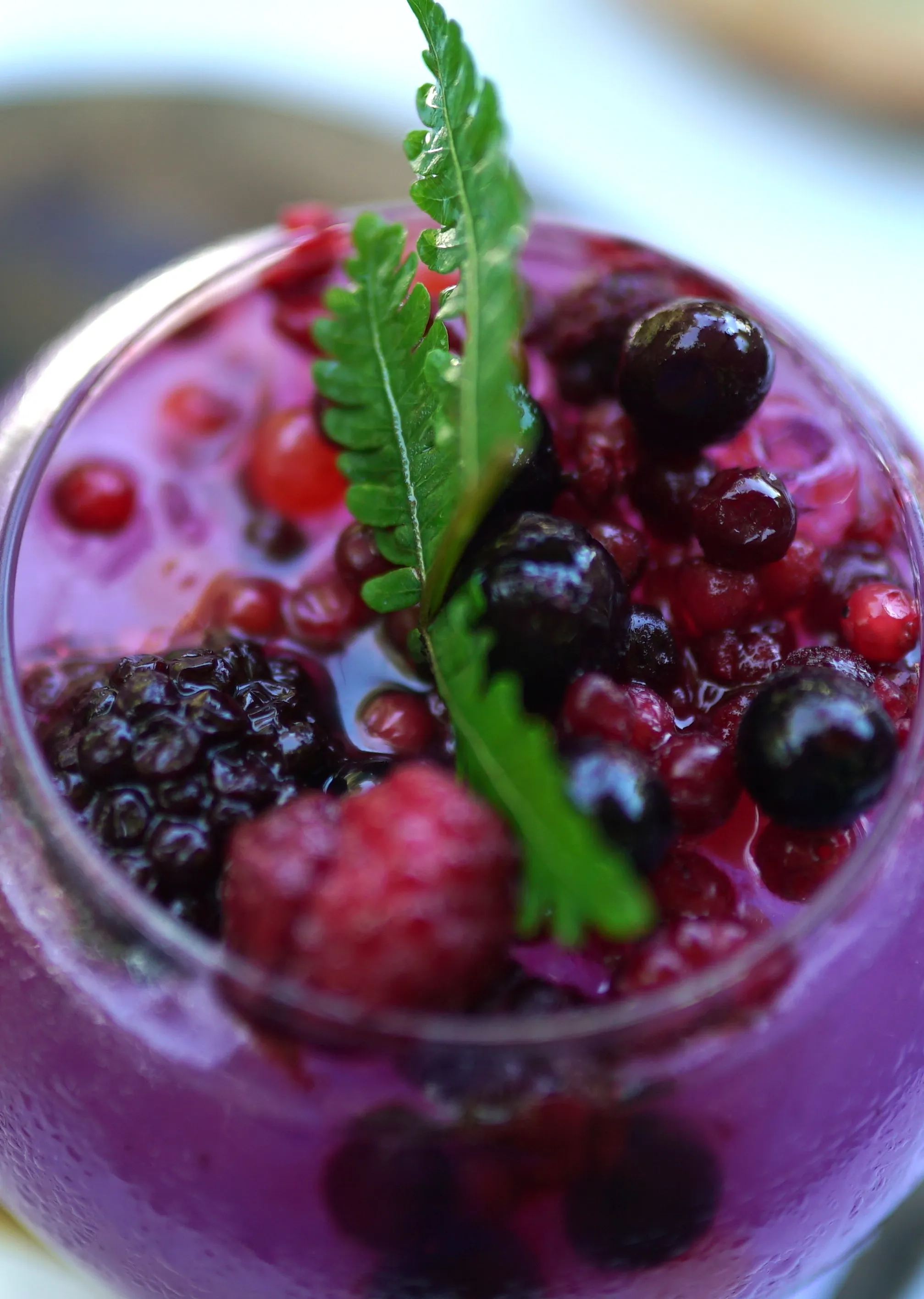 Top-down view of berry drink with fruit floating on a purple sea of syrup and melting ice