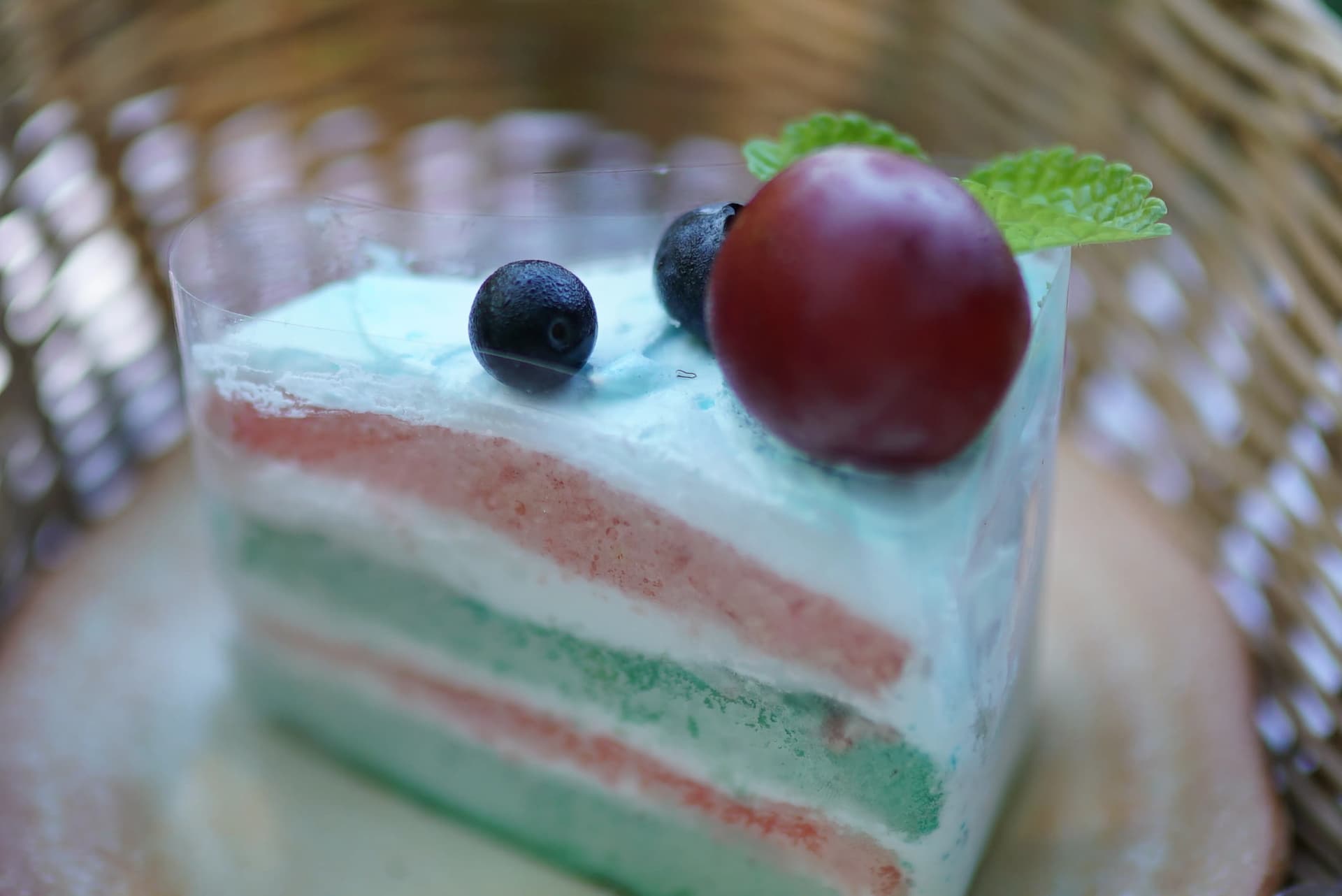 Close-up of pale blue cream topping with blueberries and fresh mint on pandan layer cake