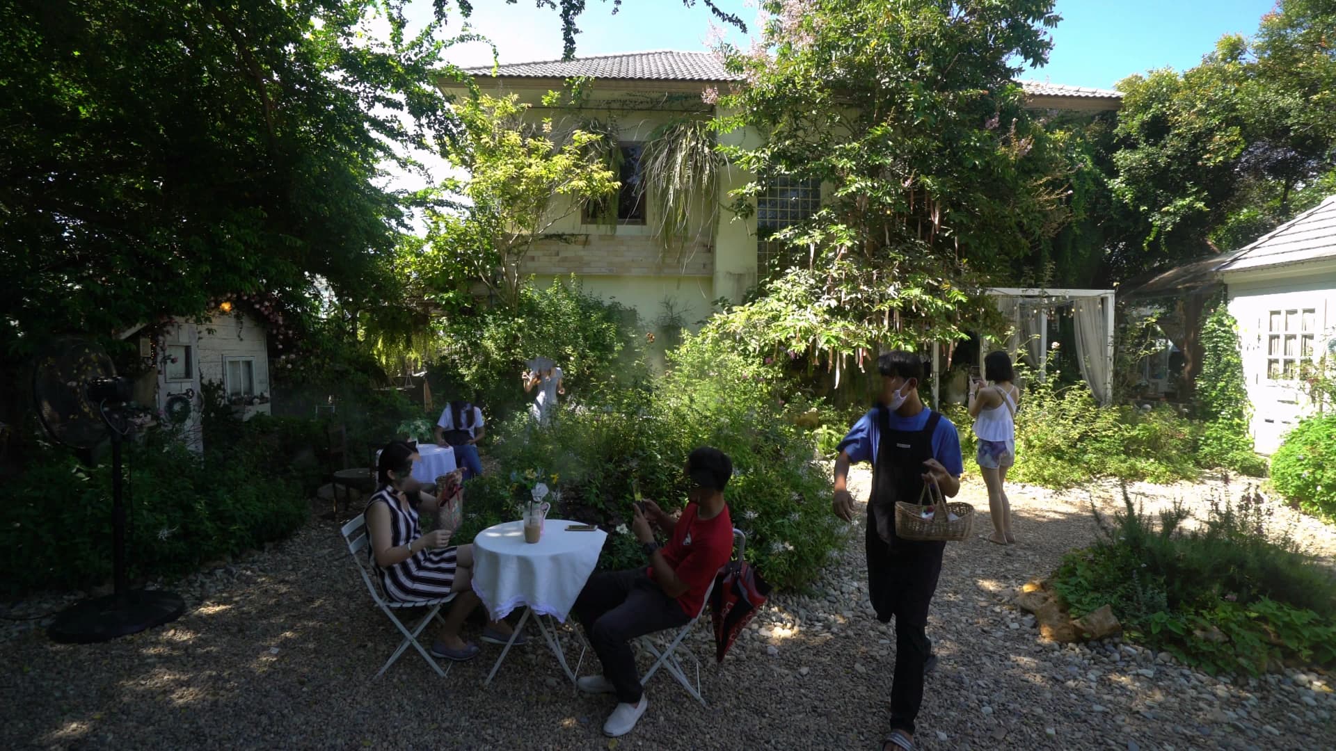 Gravel courtyard with white tables and a vine-covered two-storey building at Pa Dee in the Wild