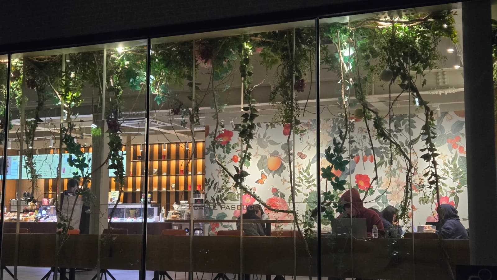 パスクッチ新灘津店の窓ガラス越しに見える花と果物の壁画とつる装飾