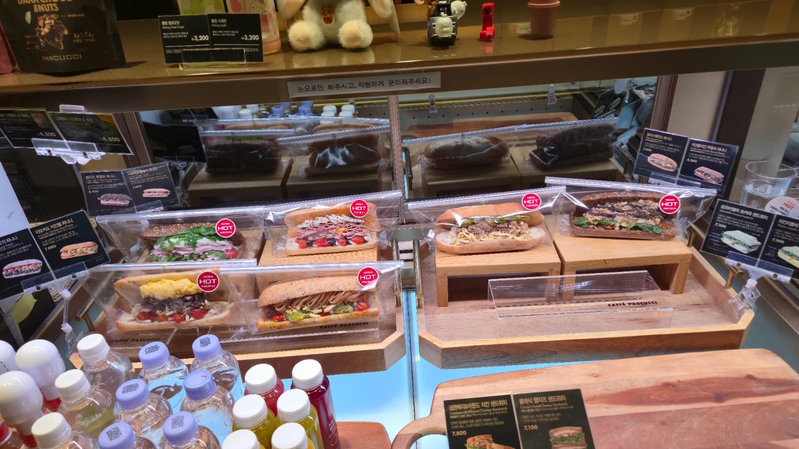 パスクッチ新灘津店パニーニコーナー — 木の台にのったパニーニと赤いHOTステッカー