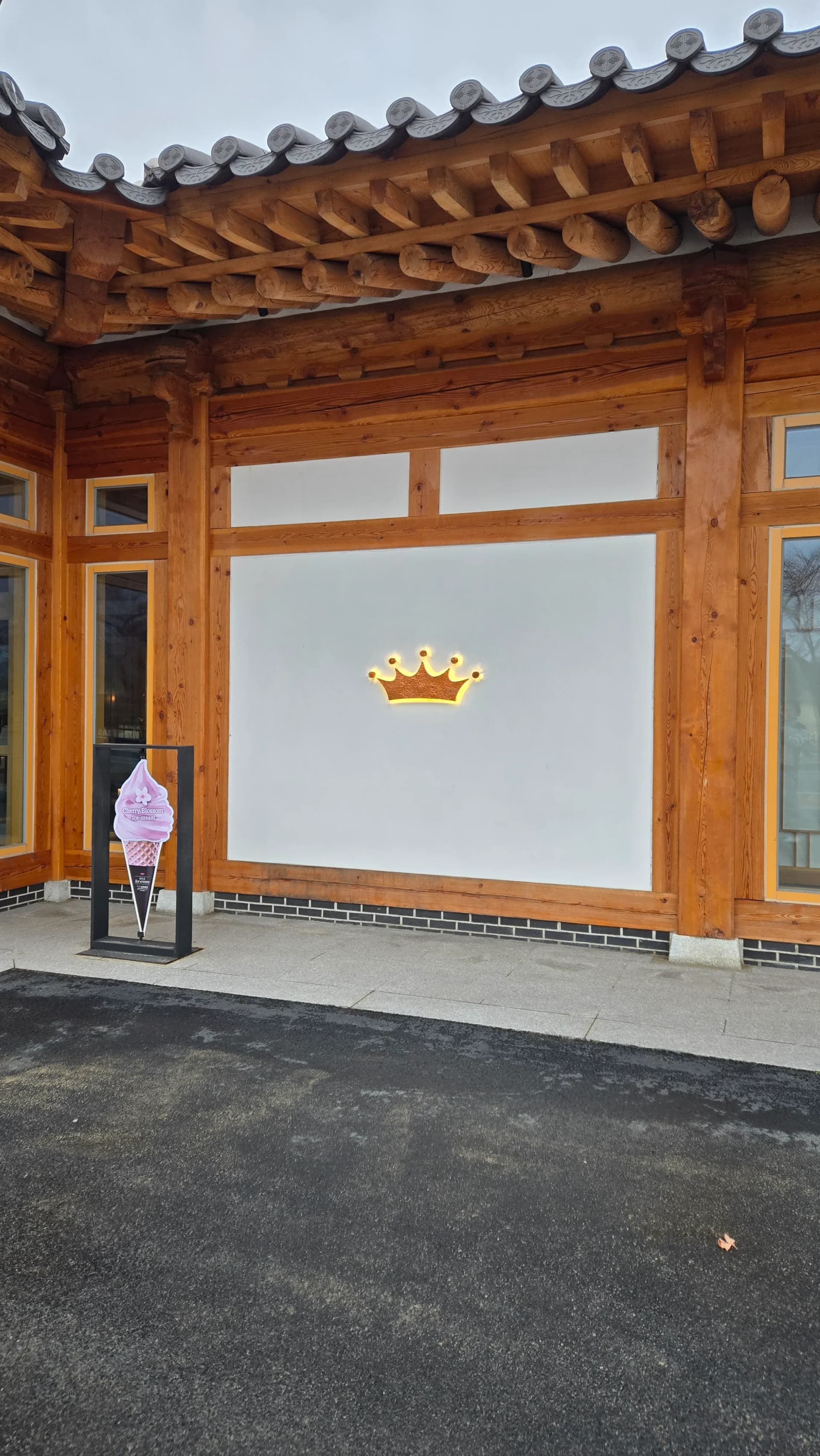 Logo vương miện Paul Bassett dưới mái hiên hanok cùng biển quảng cáo kem | 하이제이에스비