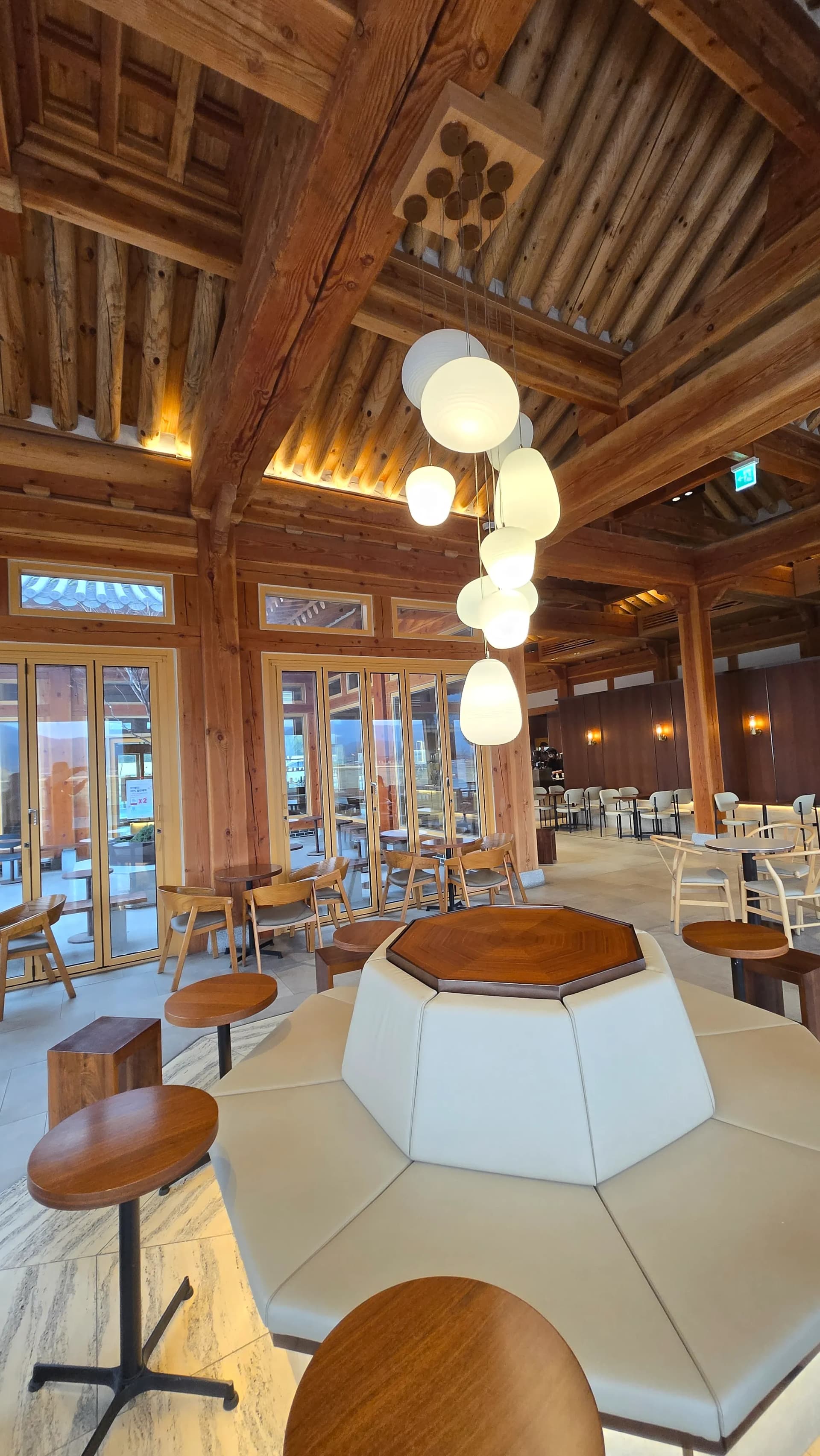 Toàn cảnh sảnh Paul Bassett Gyeongju — trần hanok, cửa kính lớn và sofa trung tâm trong một khung hình | 하이제이에스비