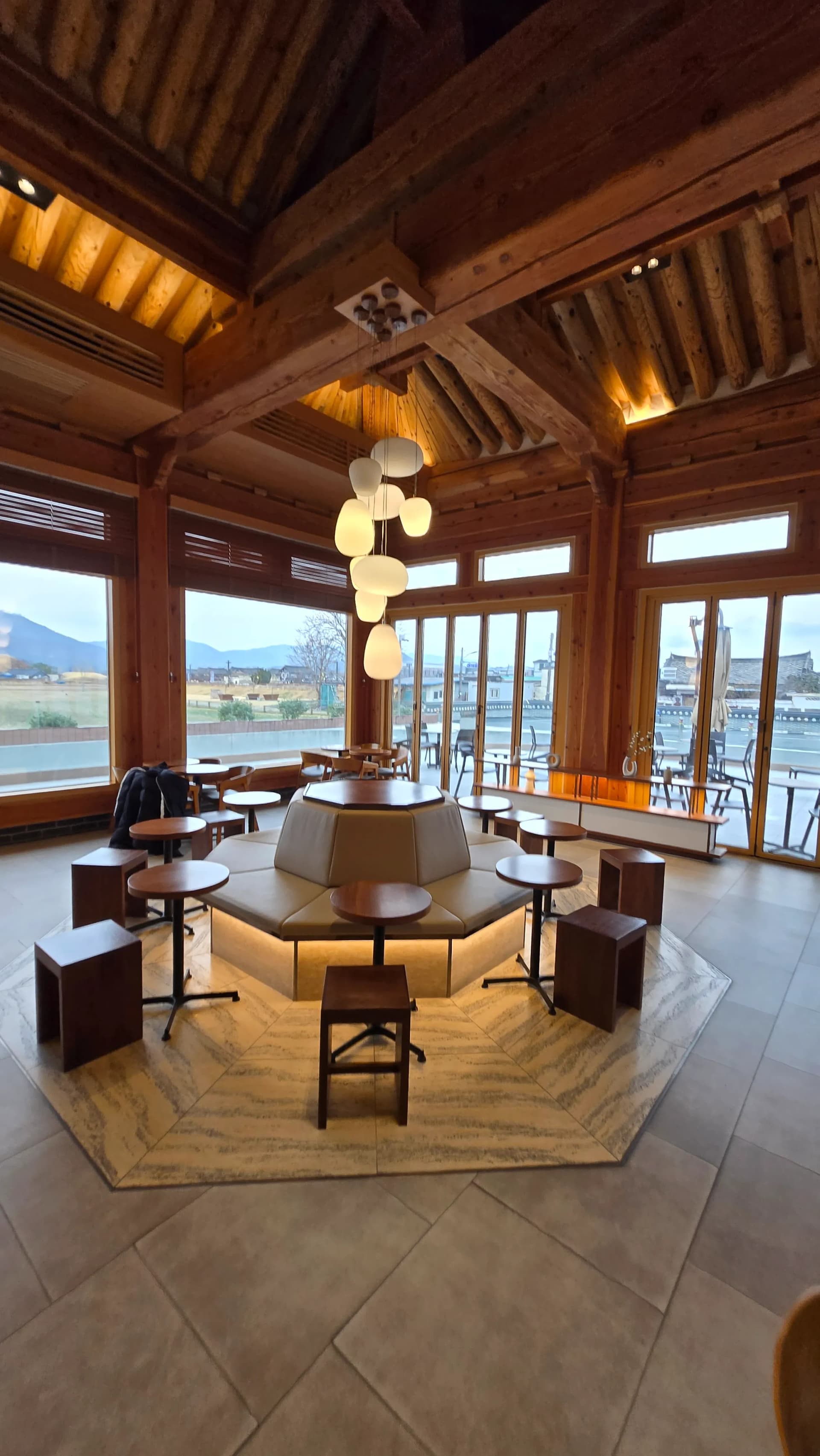 Sảnh Paul Bassett Gyeongju nhìn từ phía quầy — khoảng cách ghế thoáng và cột hanok | 하이제이에스비