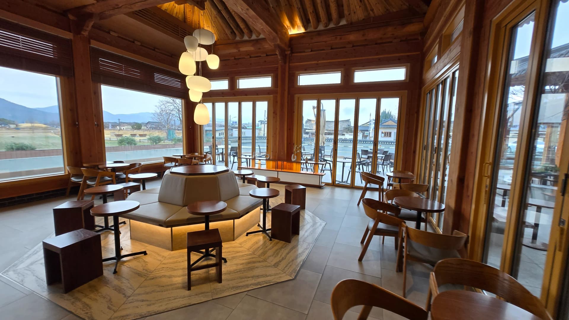 Ghế cửa sổ Paul Bassett Gyeongju — kính panorama ba mặt view phố Gyeongju, mái hanok và núi | 하이제이에스비