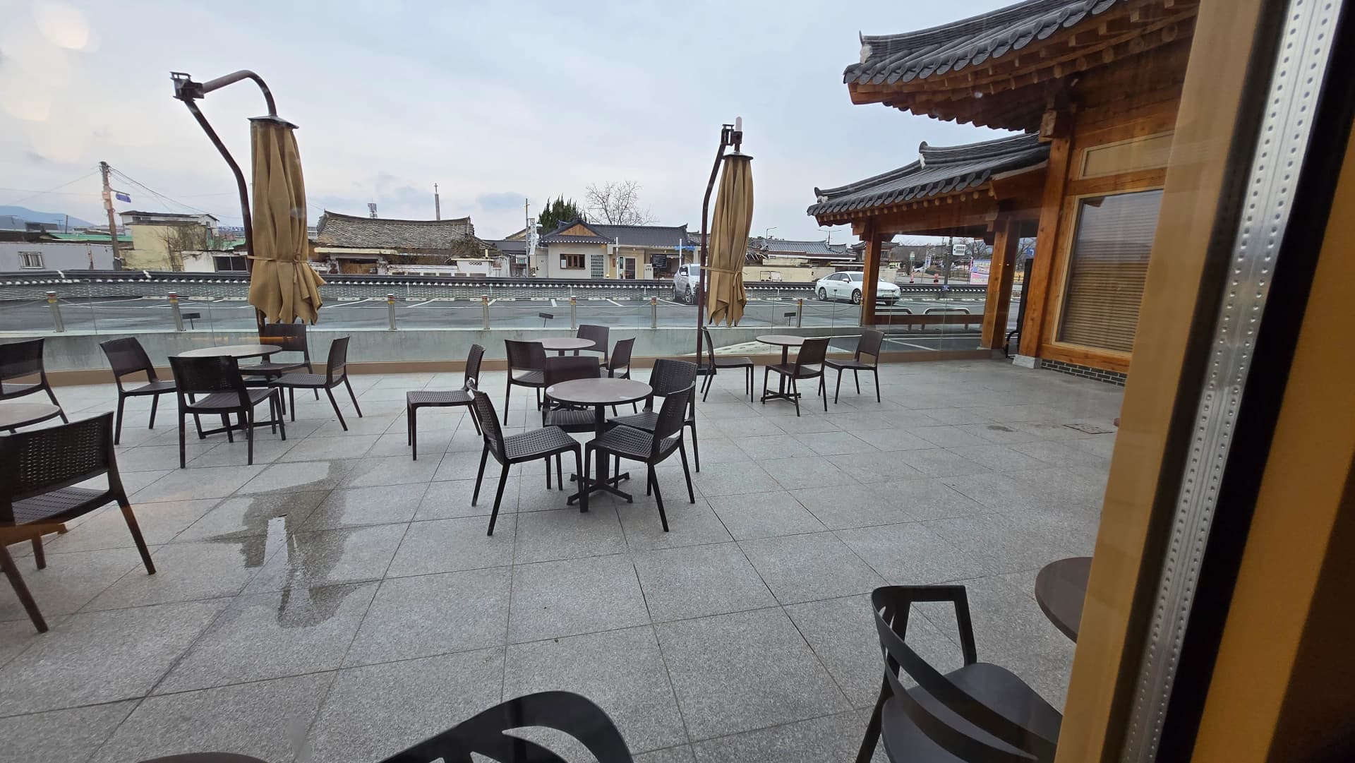 Ban công Paul Bassett Gyeongju — lan can kính với view phố Gyeongju và mái hanok | 하이제이에스비