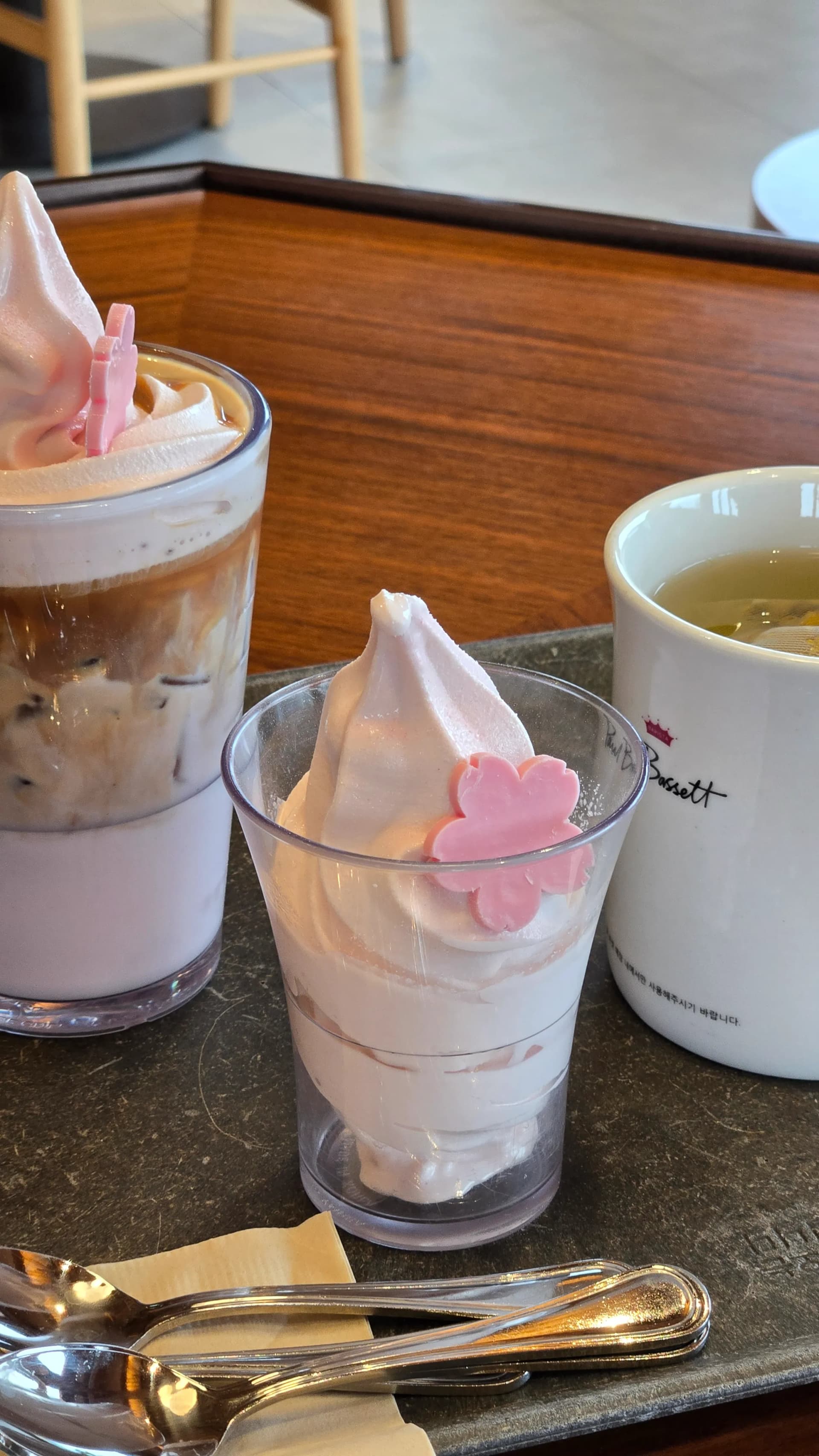 Cận cảnh kem mềm trang trí hoa anh đào hồng và ly trà Paul Bassett Gyeongju | 하이제이에스비