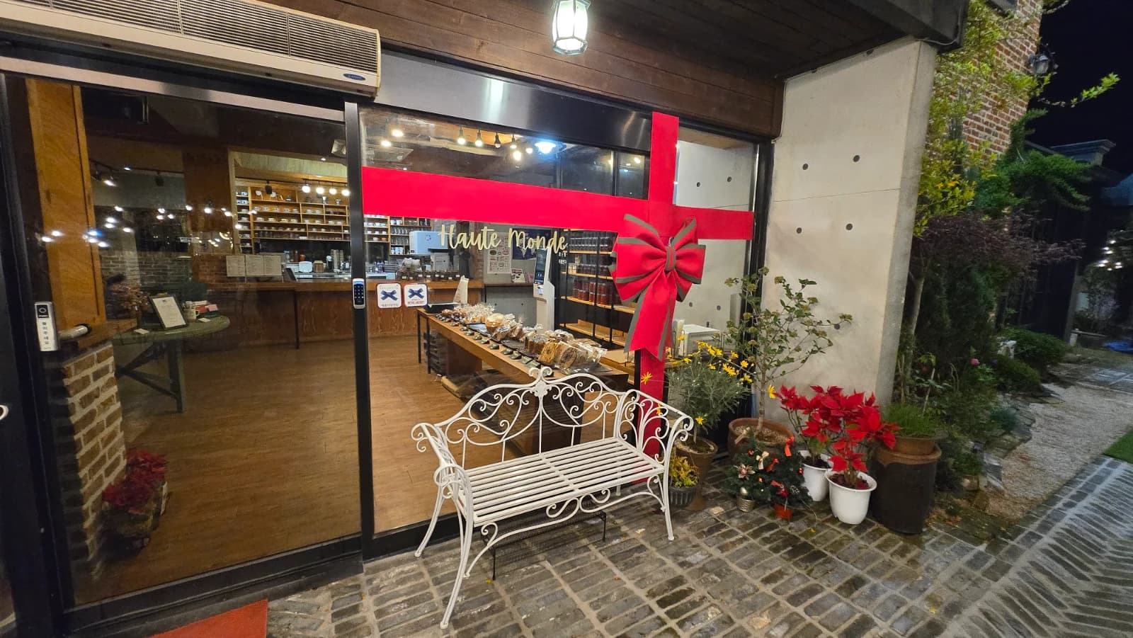 오뜨몽드 매장 입구 유리문 빨간 리본 장식과 흰색 철제 벤치