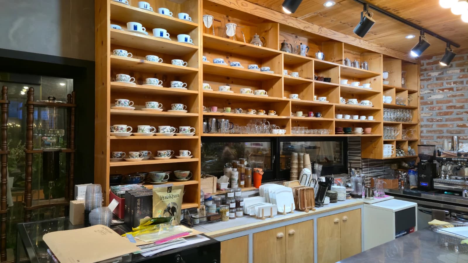 오뜨몽드 카운터 뒤쪽 나무 선반에 빼곡한 커피잔 컬렉션