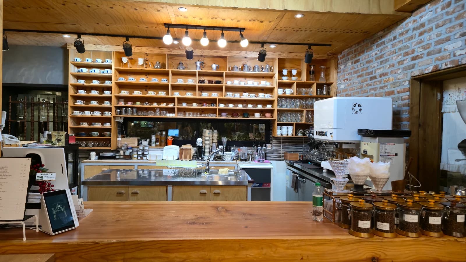 오뜨몽드 회색 벽면 선반에 진열된 찻잔과 커피 도구