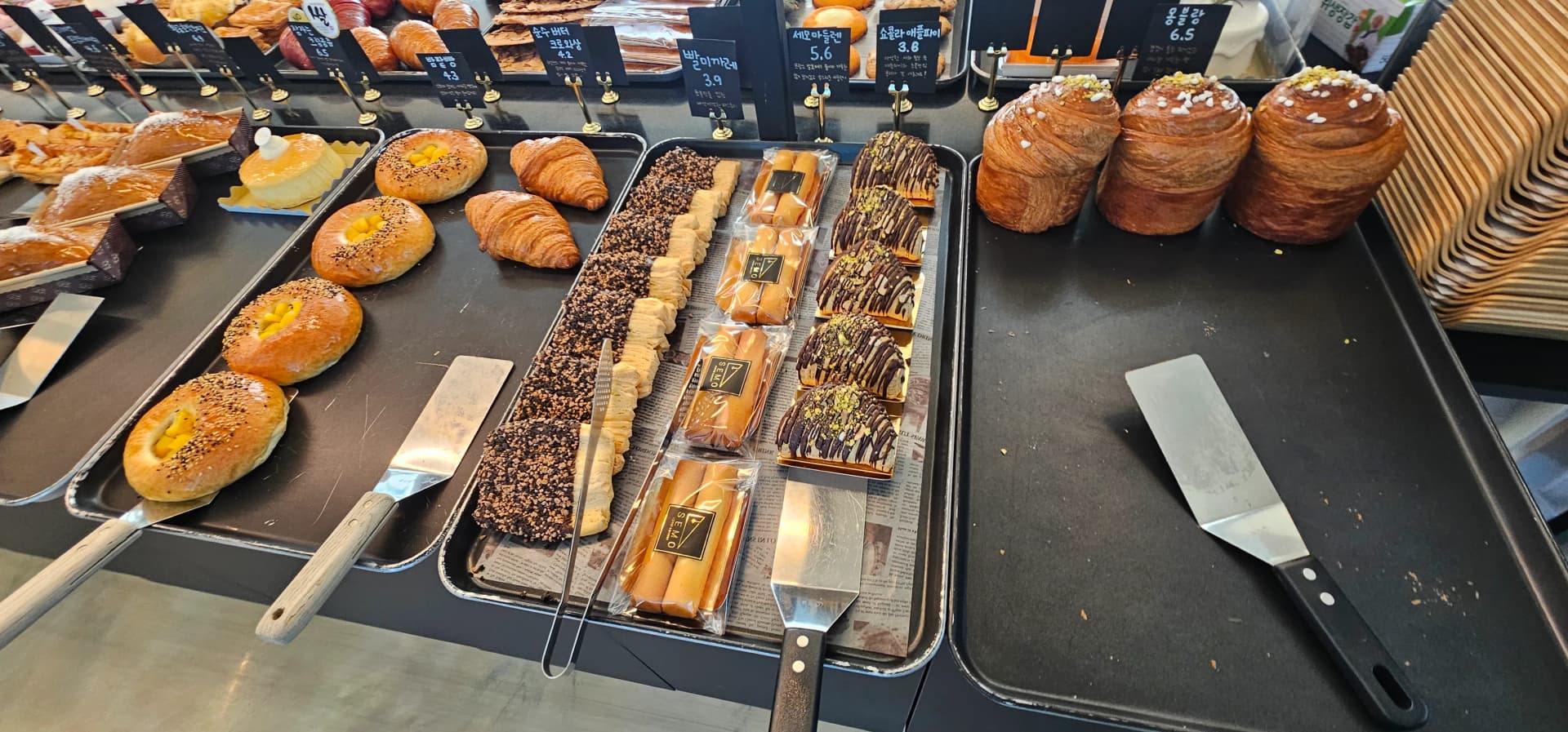 Sehemu ya kuonyesha mikate ya Semo Cafe yenye croissants, mikate ya chokoleti na aina mbalimbali za keki | 하이제이에스비