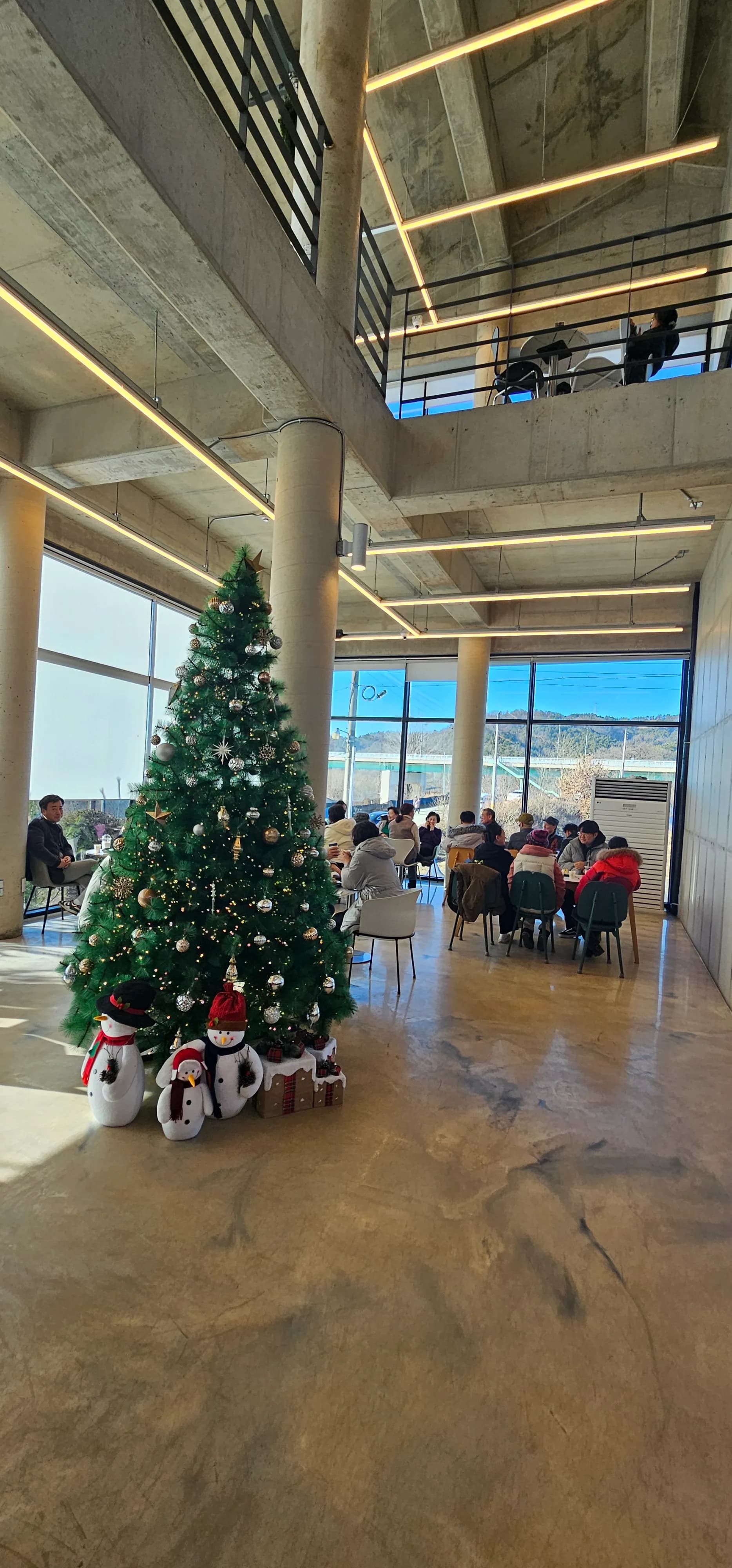 Muonekano wa ndani wa ghorofa ya kwanza ya Semo Cafe, mti wa Krismasi, mandhari ya ziwa na taa za pembe tatu | 하이제이에스비