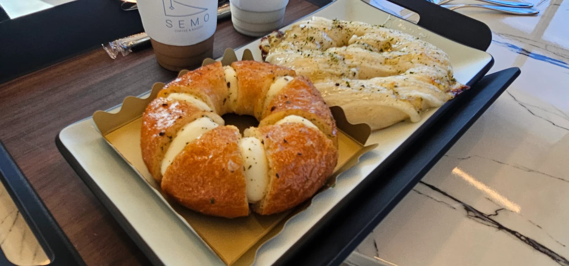 Picha ya karibu ya mikate ya Semo Cafe, tabaka za mkate wa cream na uso nyororo wa mkate wa mimea | 하이제이에스비