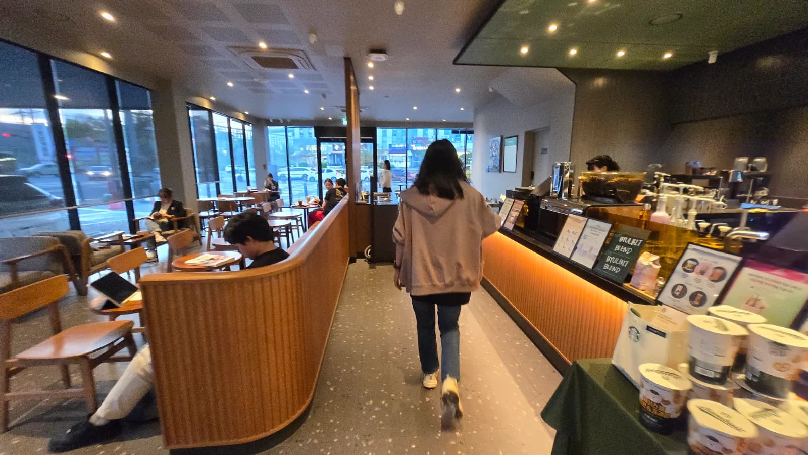 Assentos do primeiro andar do Starbucks coreano com divisórias de madeira e mesas na janela