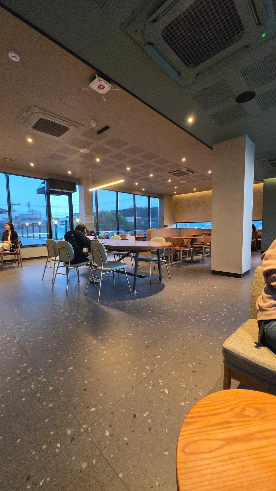 Segundo andar do Starbucks coreano com mesa redonda grande e janelas de vidro do chão ao teto