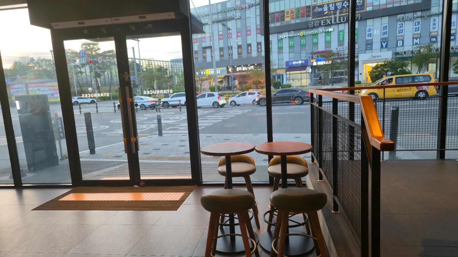 Banquetas altas na entrada do Starbucks coreano, três cadeiras com vista pra fora