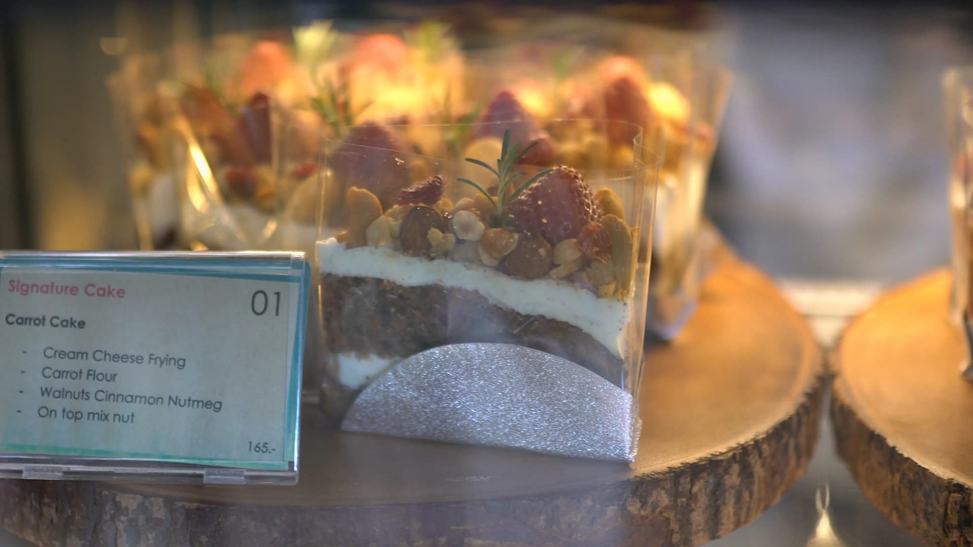 Signature carrot cake with cream cheese frosting and mixed nut topping, priced at 165 baht