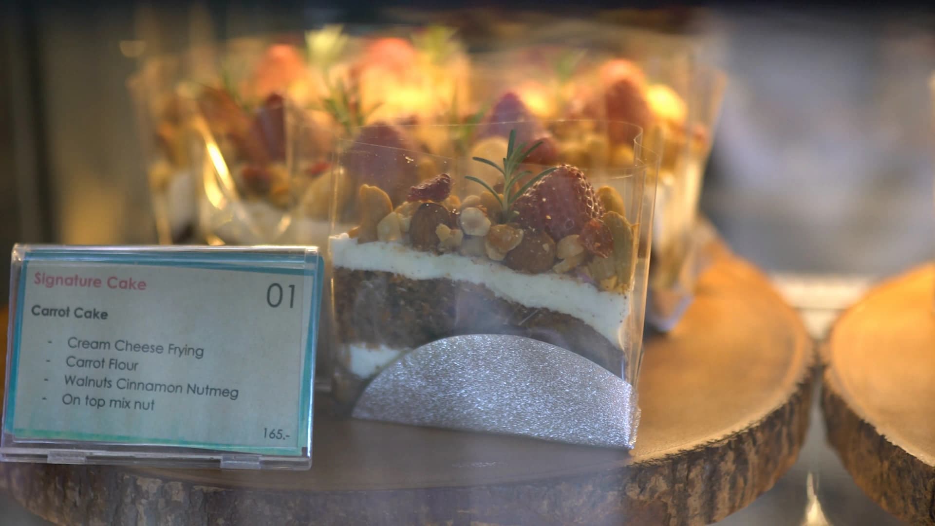 Side view of carrot cake showing distinct layers of cream cheese and carrot sponge topped with walnuts and almonds