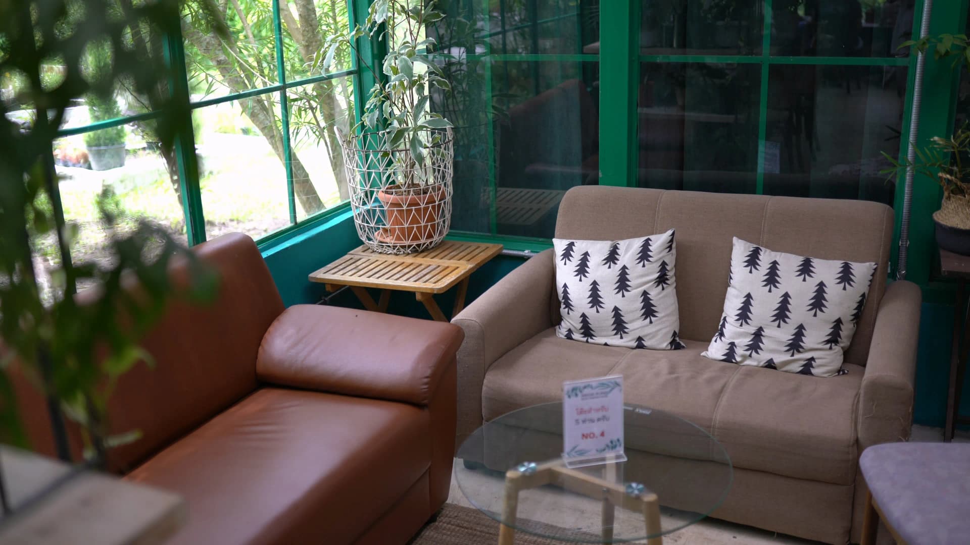 Air-conditioned indoor seating at The Creeper House with leather sofas and green iron-framed windows overlooking the garden
