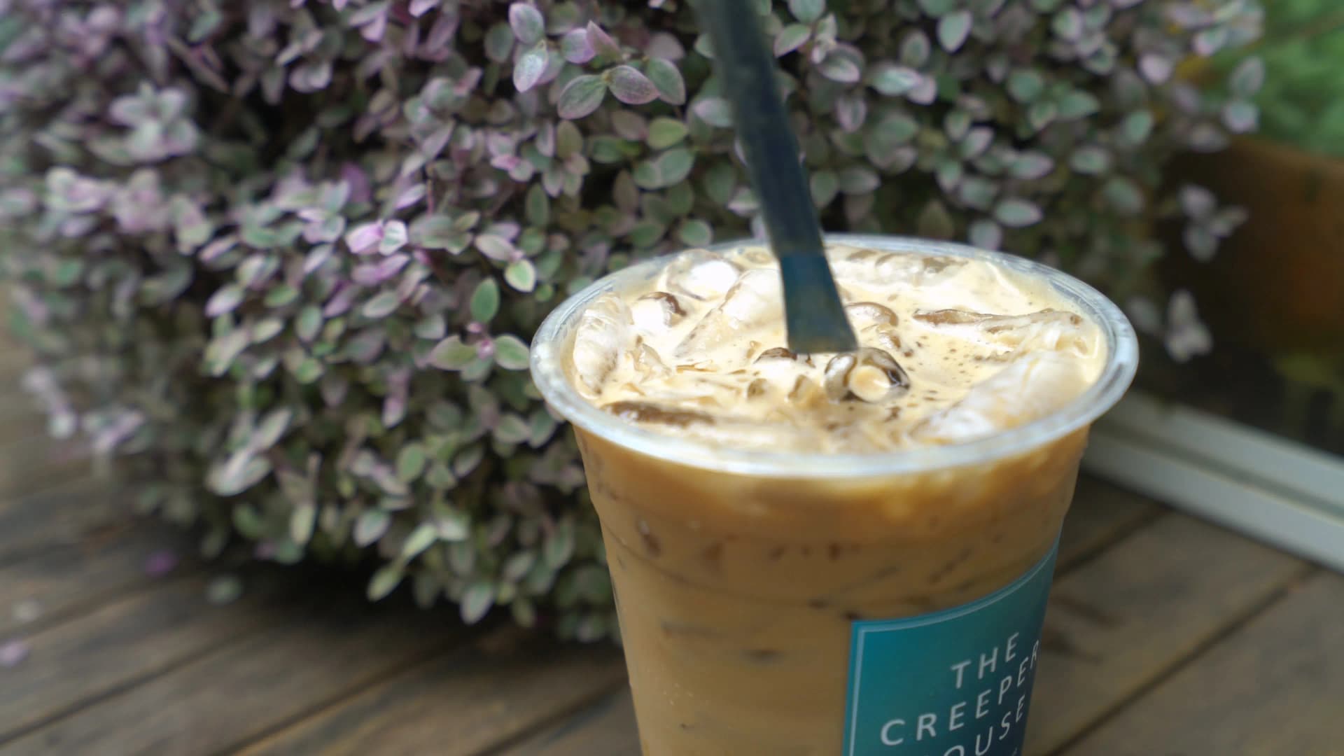 Caramel macchiato with lid removed showing caramel swirled with ice in a brown-toned drink