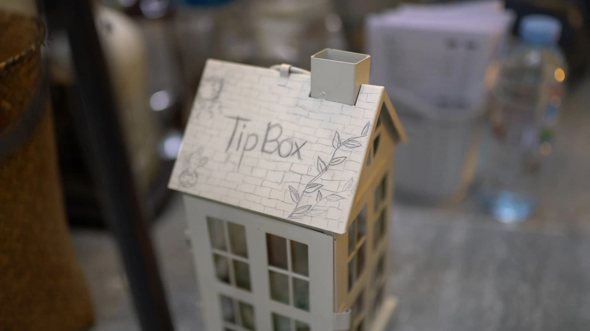 White miniature house-shaped tip box with pencil-drawn brick pattern and leaves on the roof