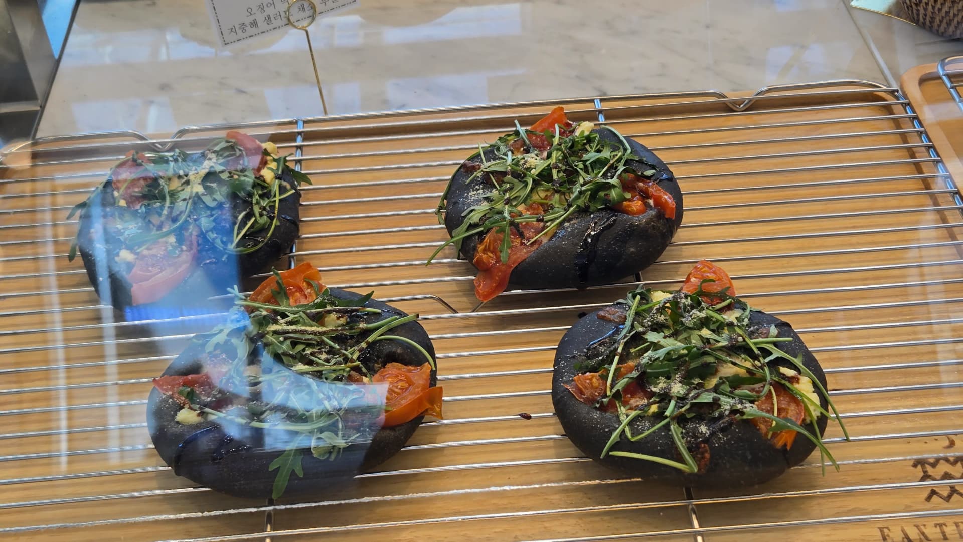 Achịcha nwere dough ojii, a tinyere arugula na cherry tomato n’elu | 하이제이에스비