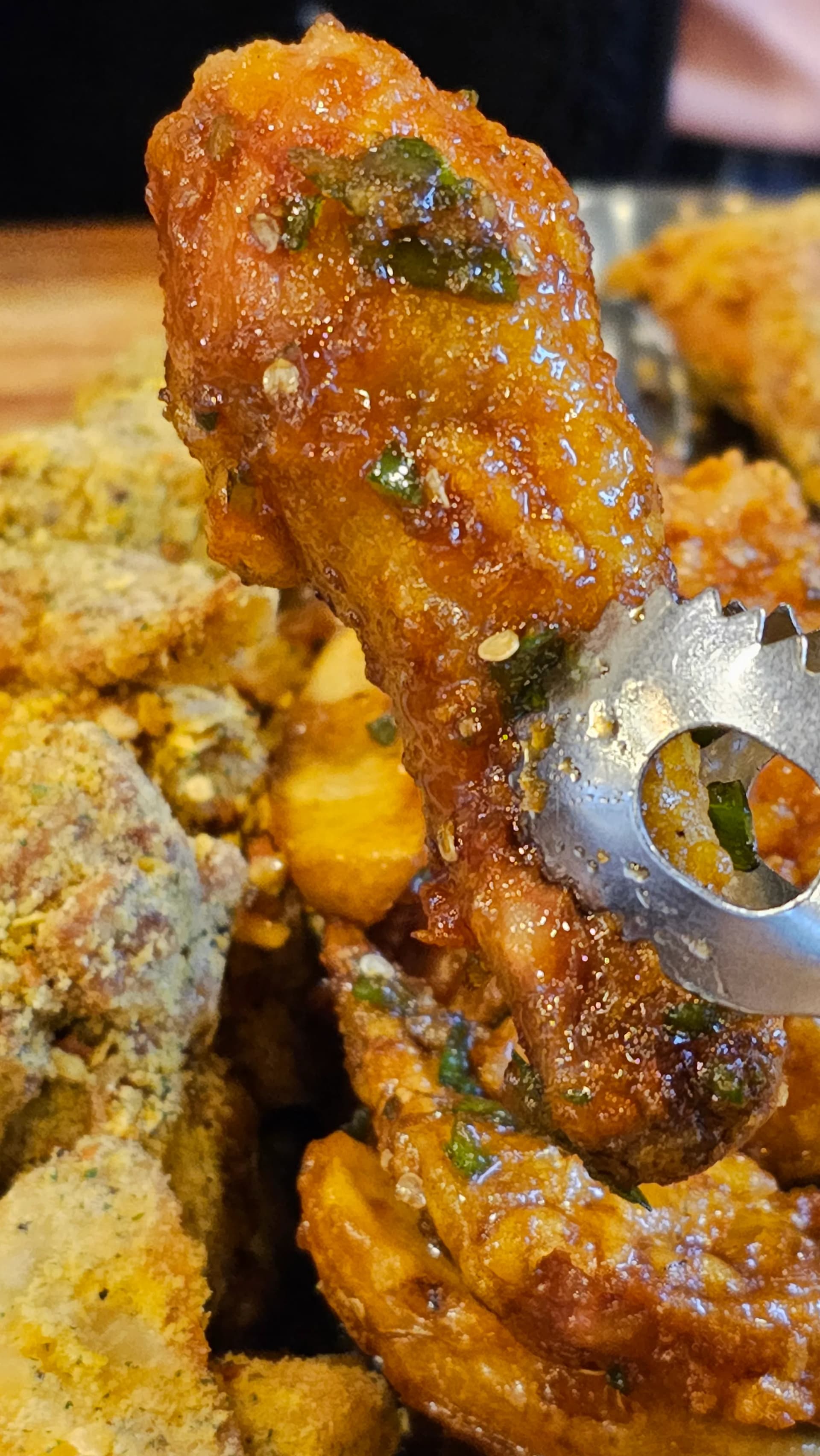 ملقط يمسك قطعة فخذ دجاج مغطاة بصلصة الفلفل الحار من طبق نص ونص في 60 غي تشيكن