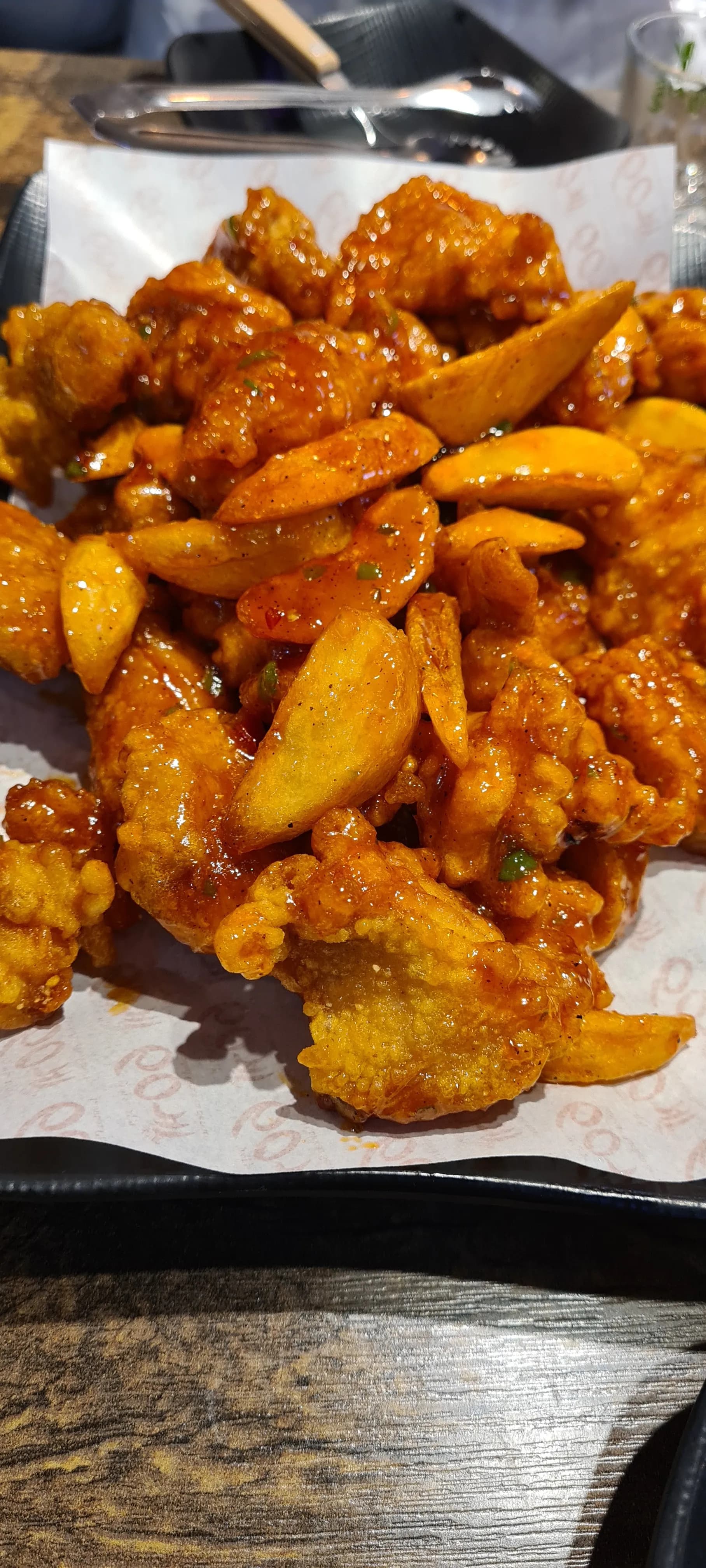 دجاج الـ6 ثوانٍ بدون عظم من 60 غي تشيكن مع صلصة حارة لامعة تغطي قطع الدجاج وشرائح البطاطا الودجز