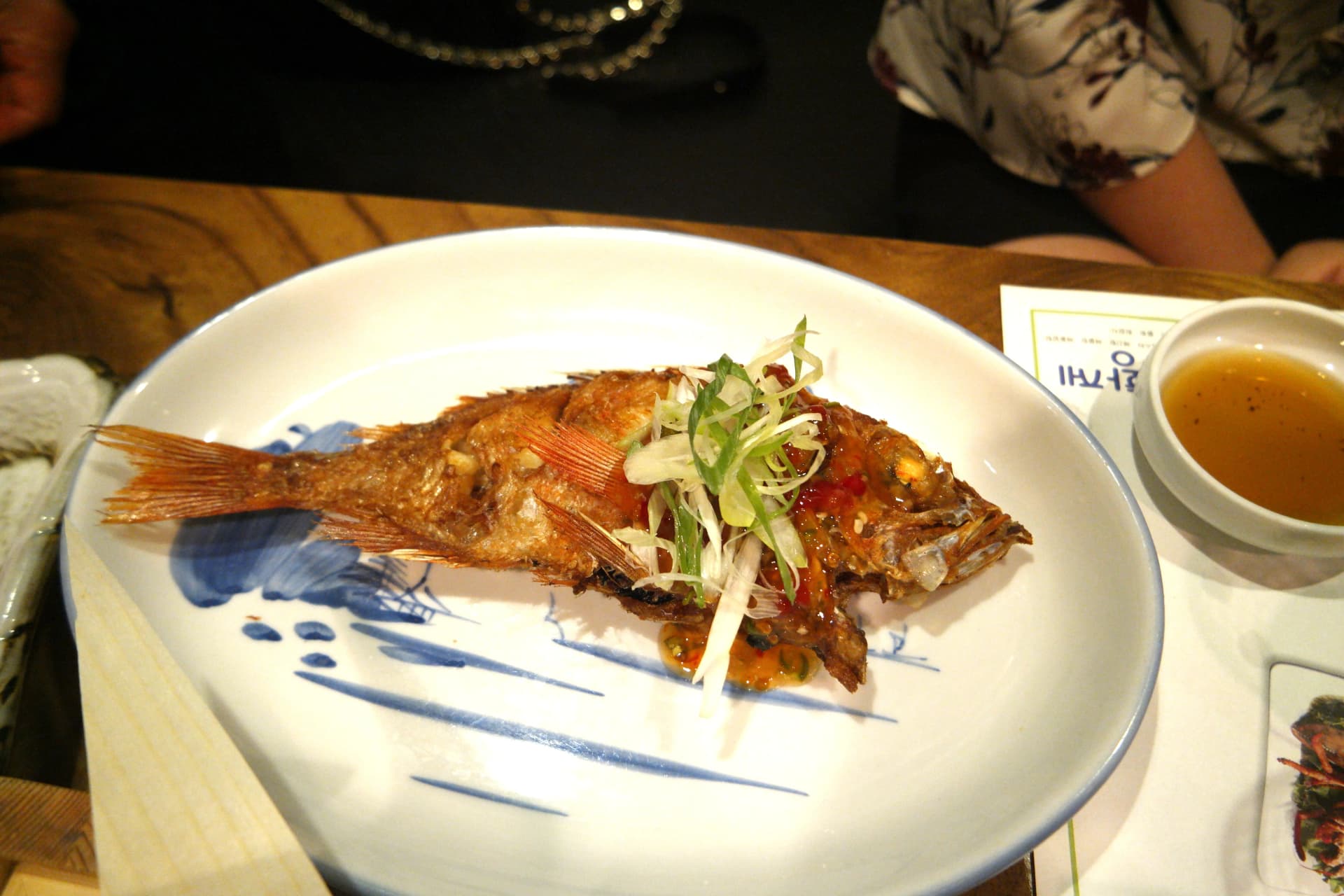 Samaki mzima aliyekaangwa akiwa na mchuzi wa pilipili na nira zilizokatakatwa juu yake | 하이제이에스비