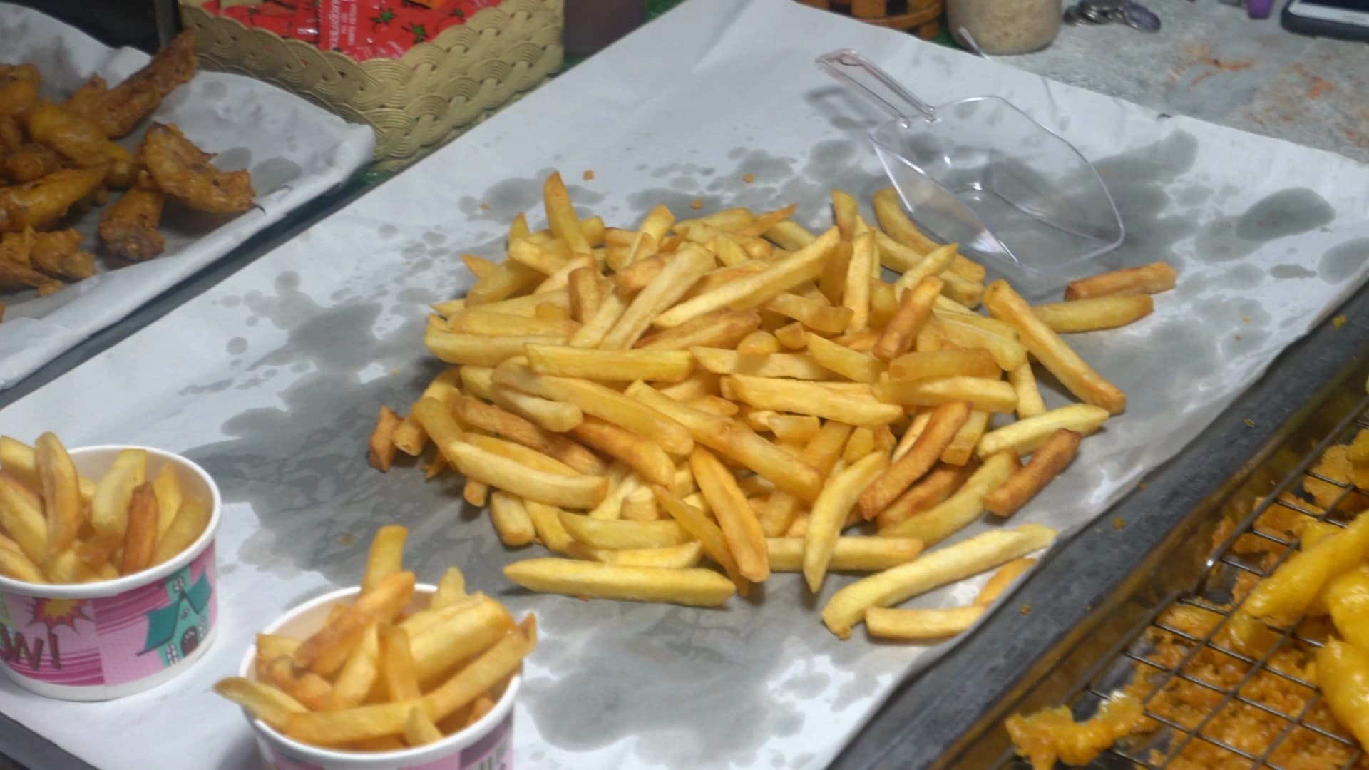 태국 시장 입구 튀김 가판대 – 감자튀김이 종이 위에 수북하게 쌓여 있는 모습