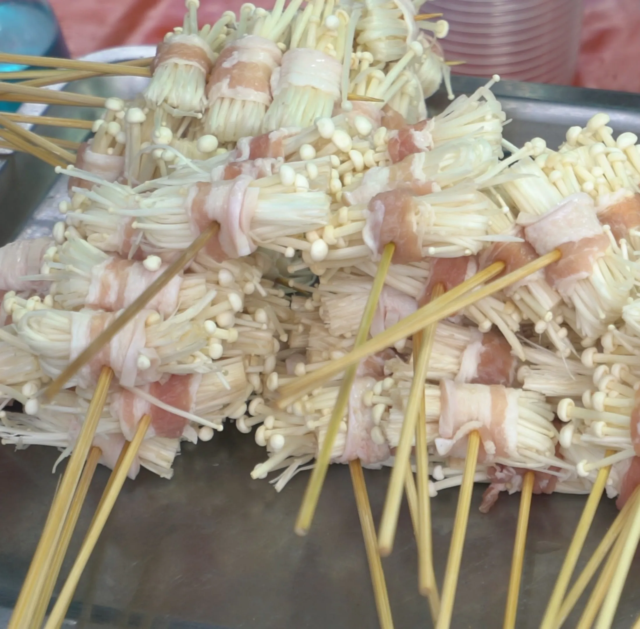 태국 시장 팽이버섯 베이컨말이 꼬치 – 굽기 전 날것 상태로 쌓여 있는 모습