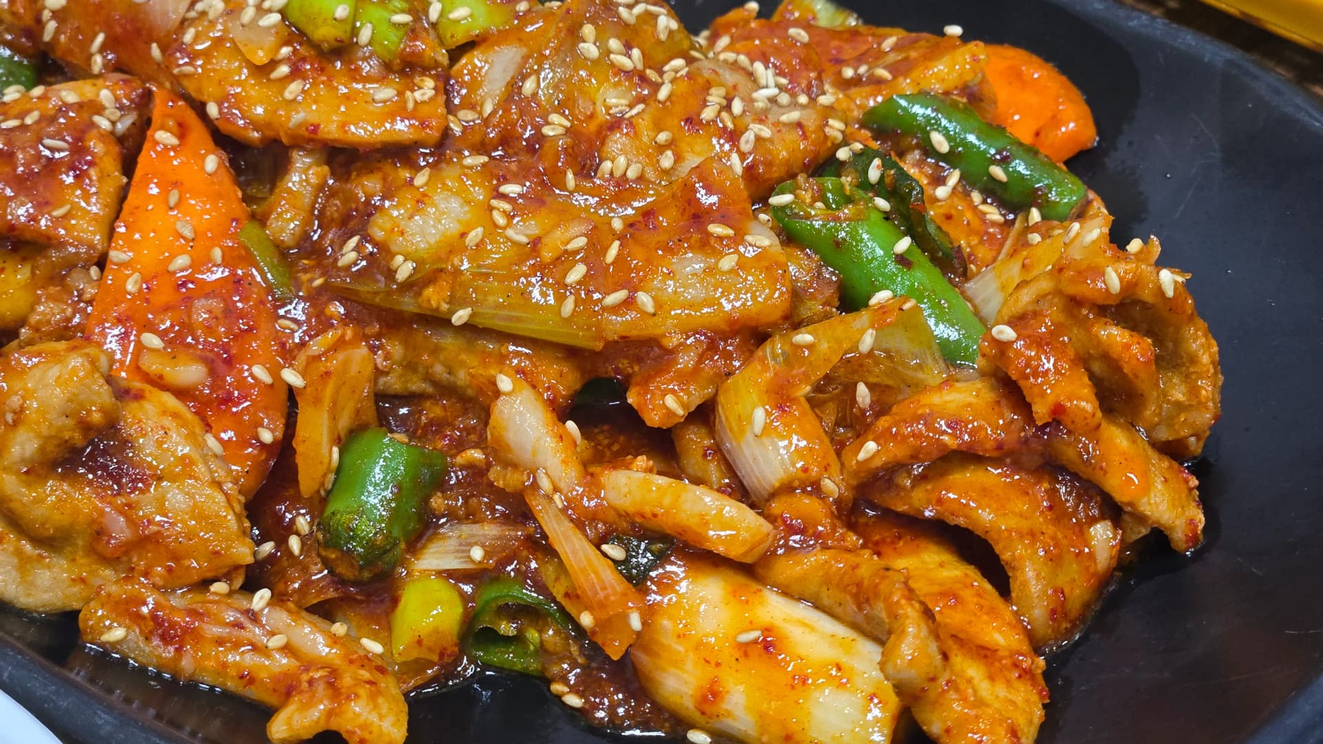 제육볶음 초근접 촬영 - 도톰하게 썬 돼지고기에 고추장 양념이 졸아붙어 윤기가 나는 모습 | 하이제이에스비