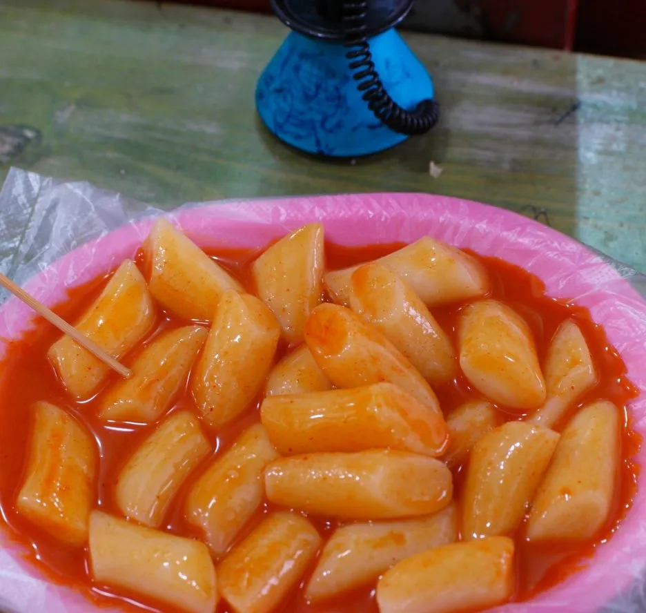 Top-down view of a bunsik plate loaded with only rice cakes in spicy sauce | 하이제이에스비