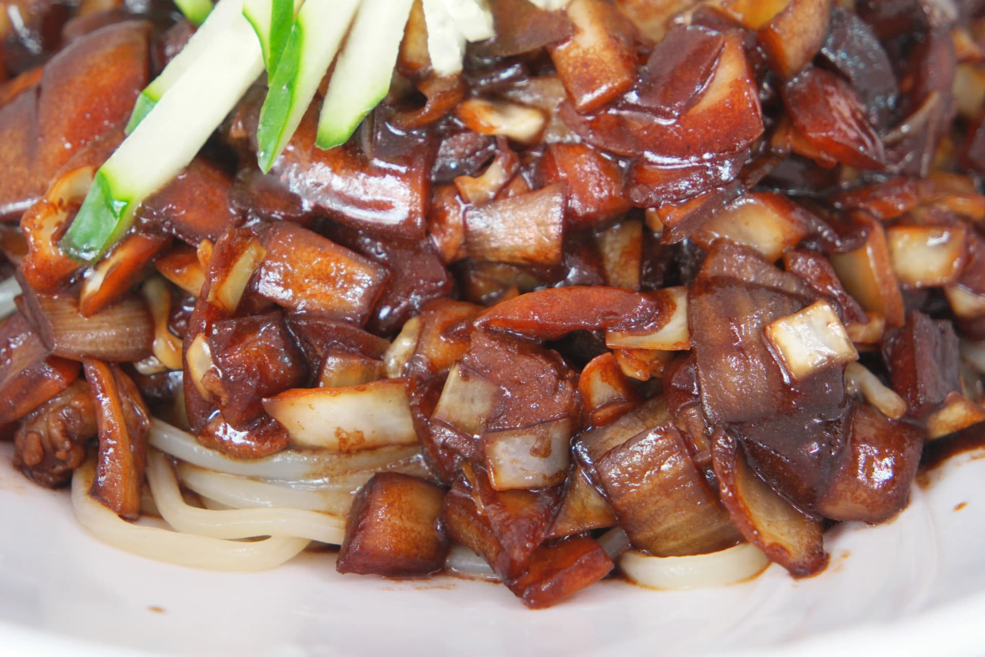 짜장면 클로즈업, 춘장 소스가 면 사이사이로 스며들고 돼지고기와 양파가 큼직하게 썰려 있는 모습 | 하이제이에스비