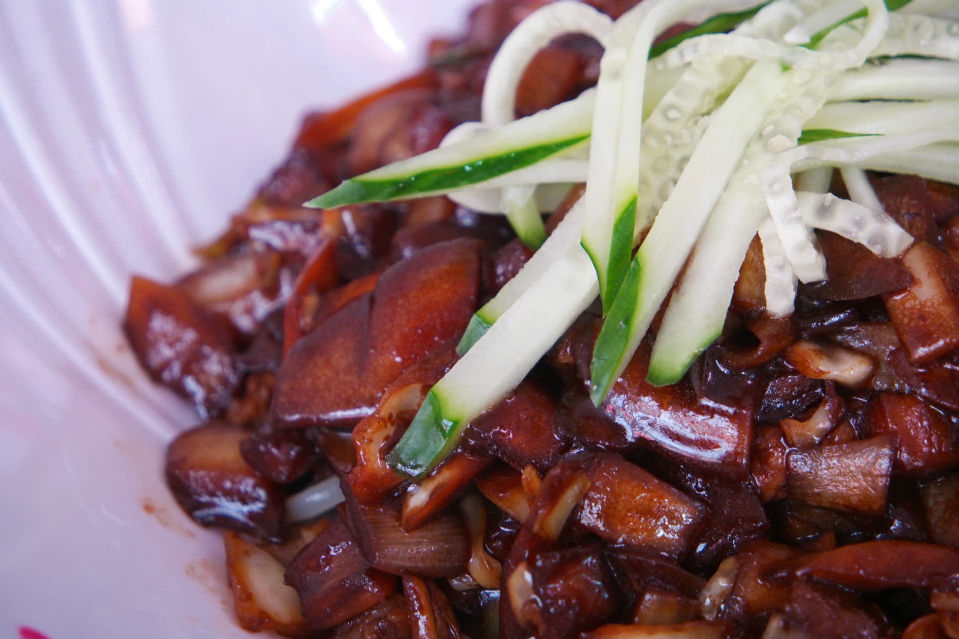 짜장면 소스 디테일, 캐러멜화된 양파와 춘장 소스가 재료를 감싸고 채 썬 오이가 올라간 앵글 | 하이제이에스비